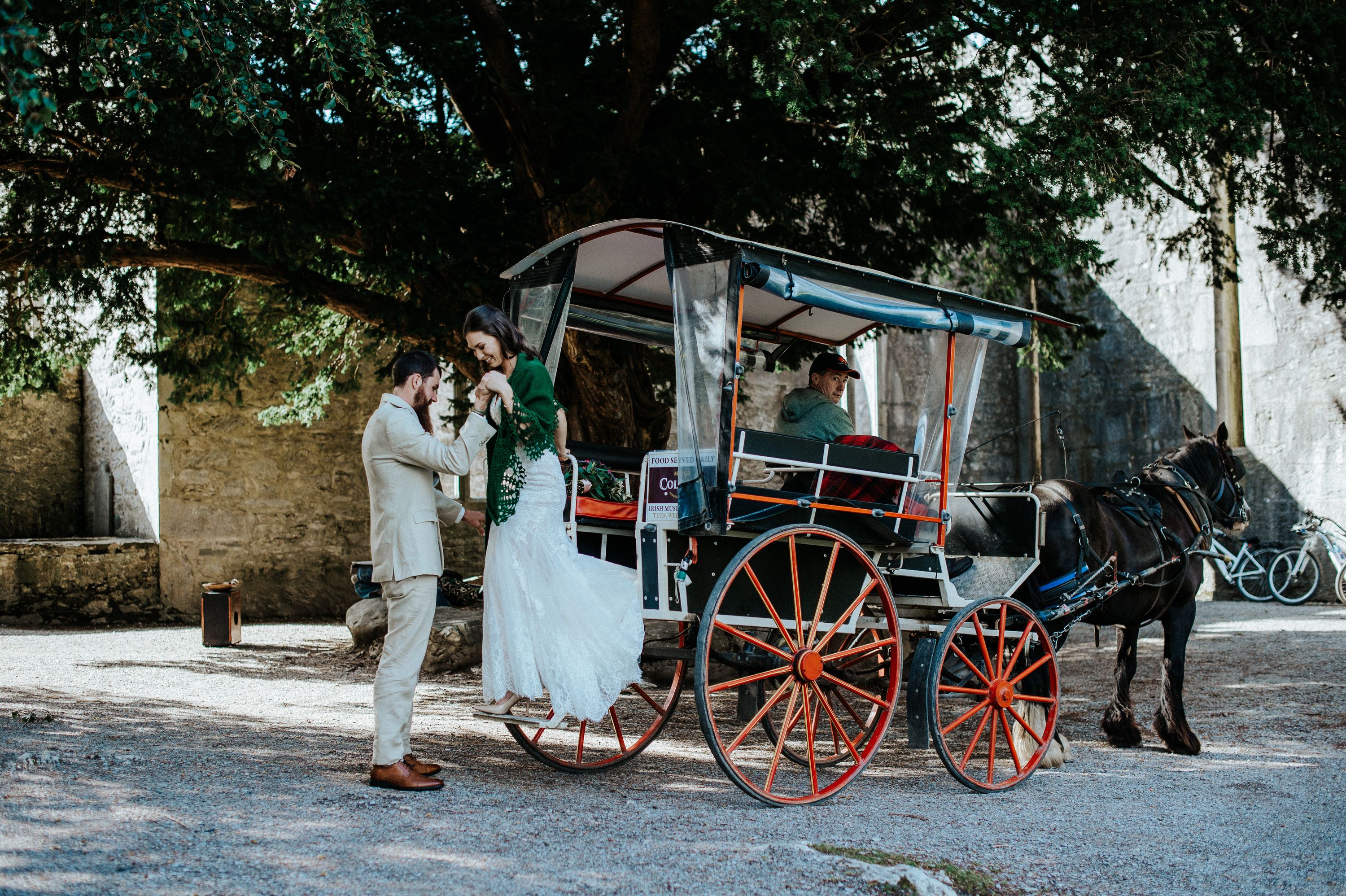 A wedding couple exiting a horse-drawn carriage in Ireland
