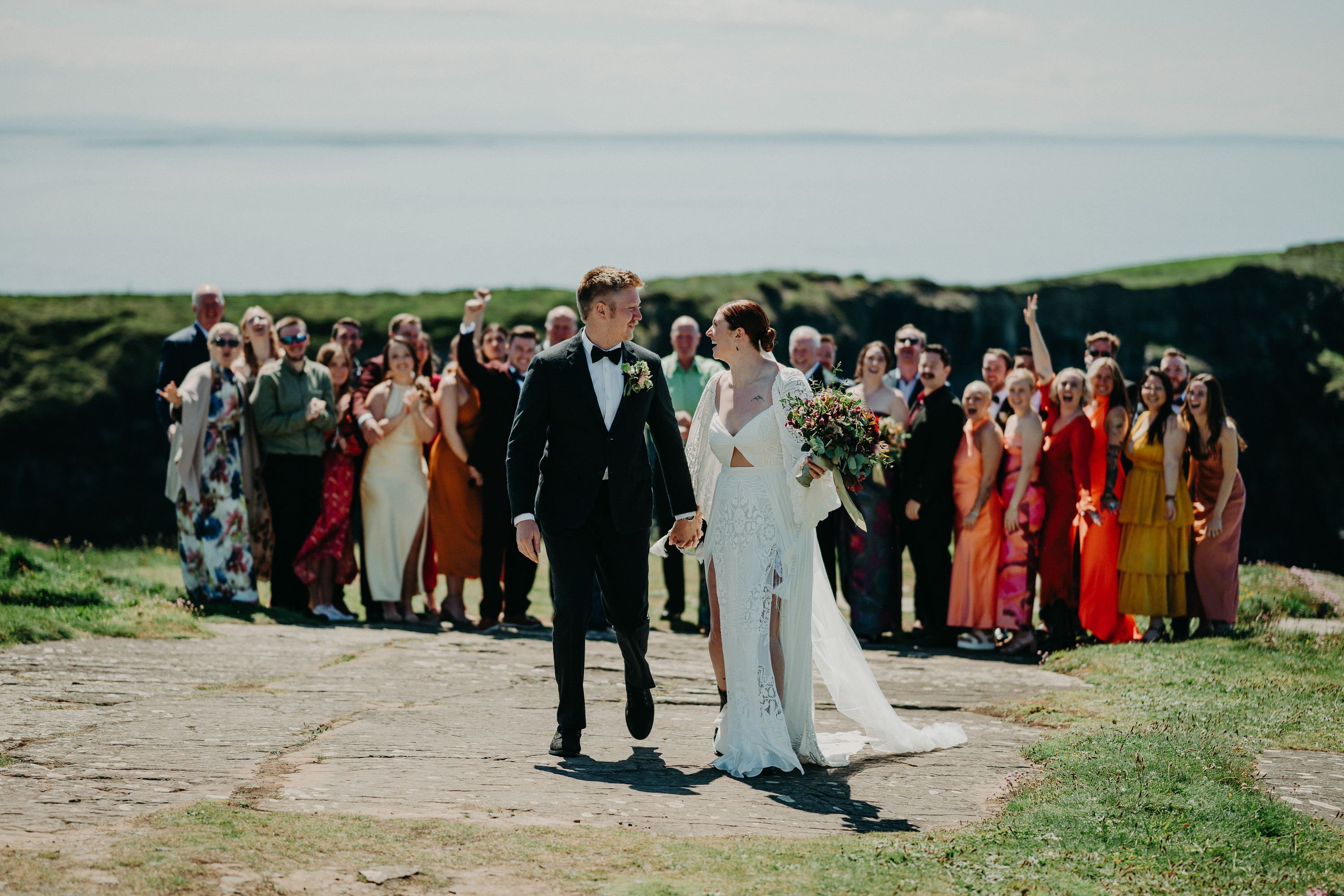 A bride and groom celebrating with their entire party during a small wedding in Ireland on top of a cliff