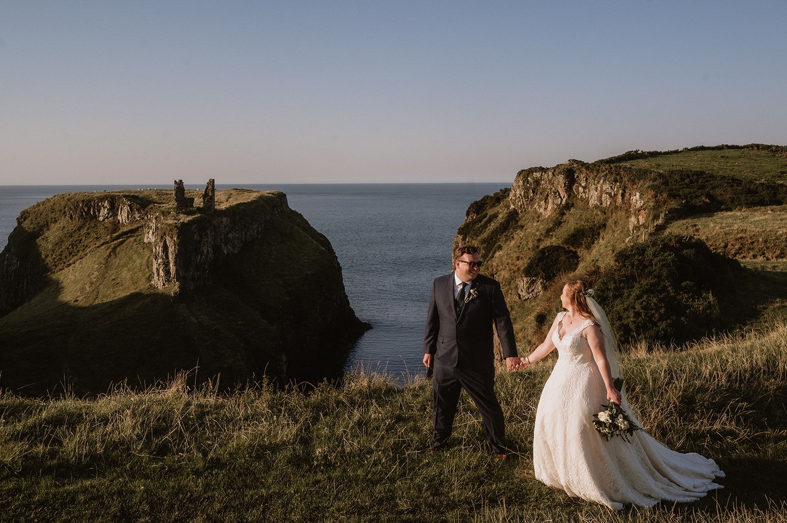 Bride and groom walks happily atop the cliffs during the photoshoot of their vow renewal in Ireland