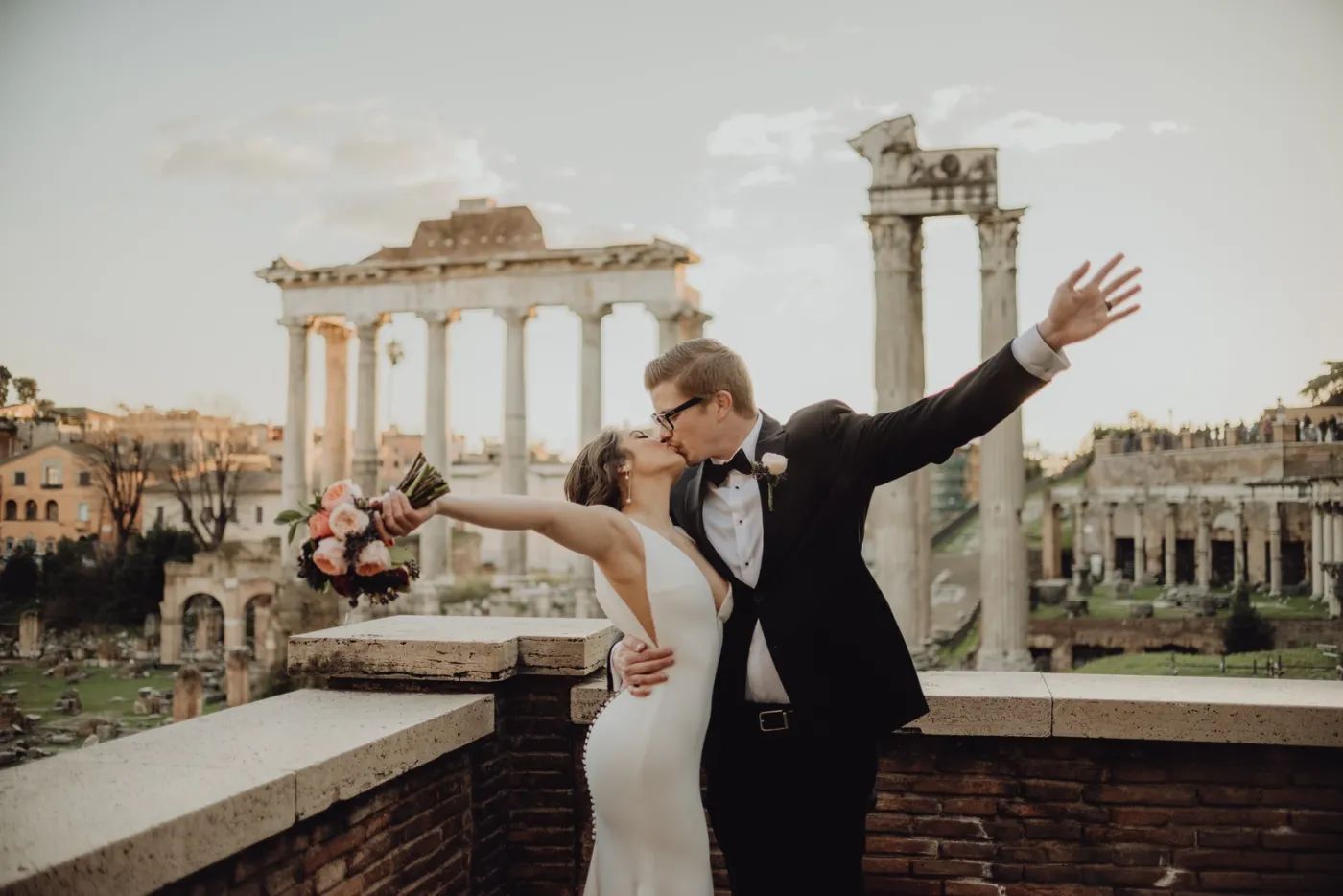 Bride and groom atop a terrace with the Colosseum and the Roman Forum in the background during their elopement in Italy