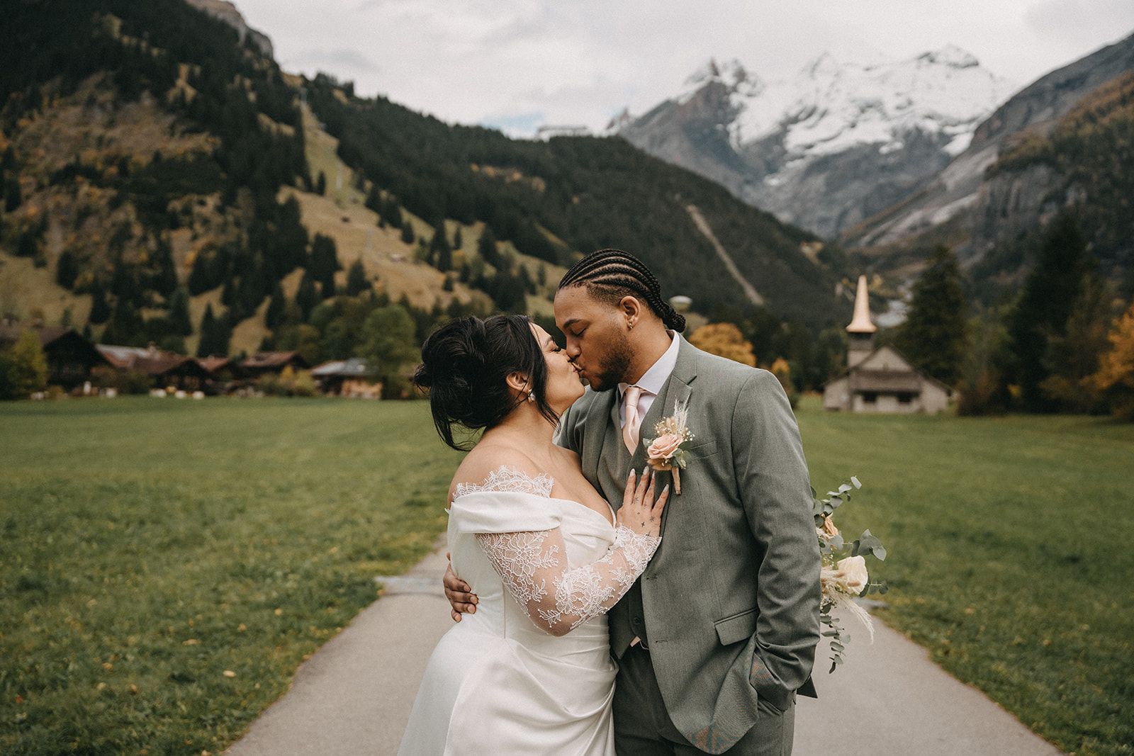Groom kisses bride on her forehead in Switzerland with mountains in the background