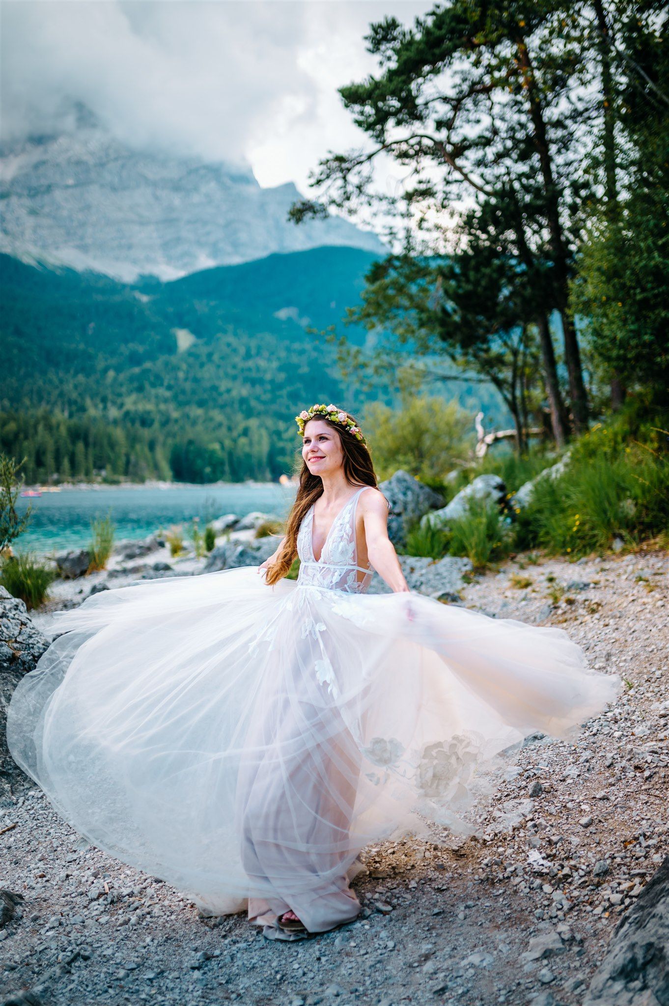 A bride dancing lakeside with the mountains behind for her small wedding in Germany