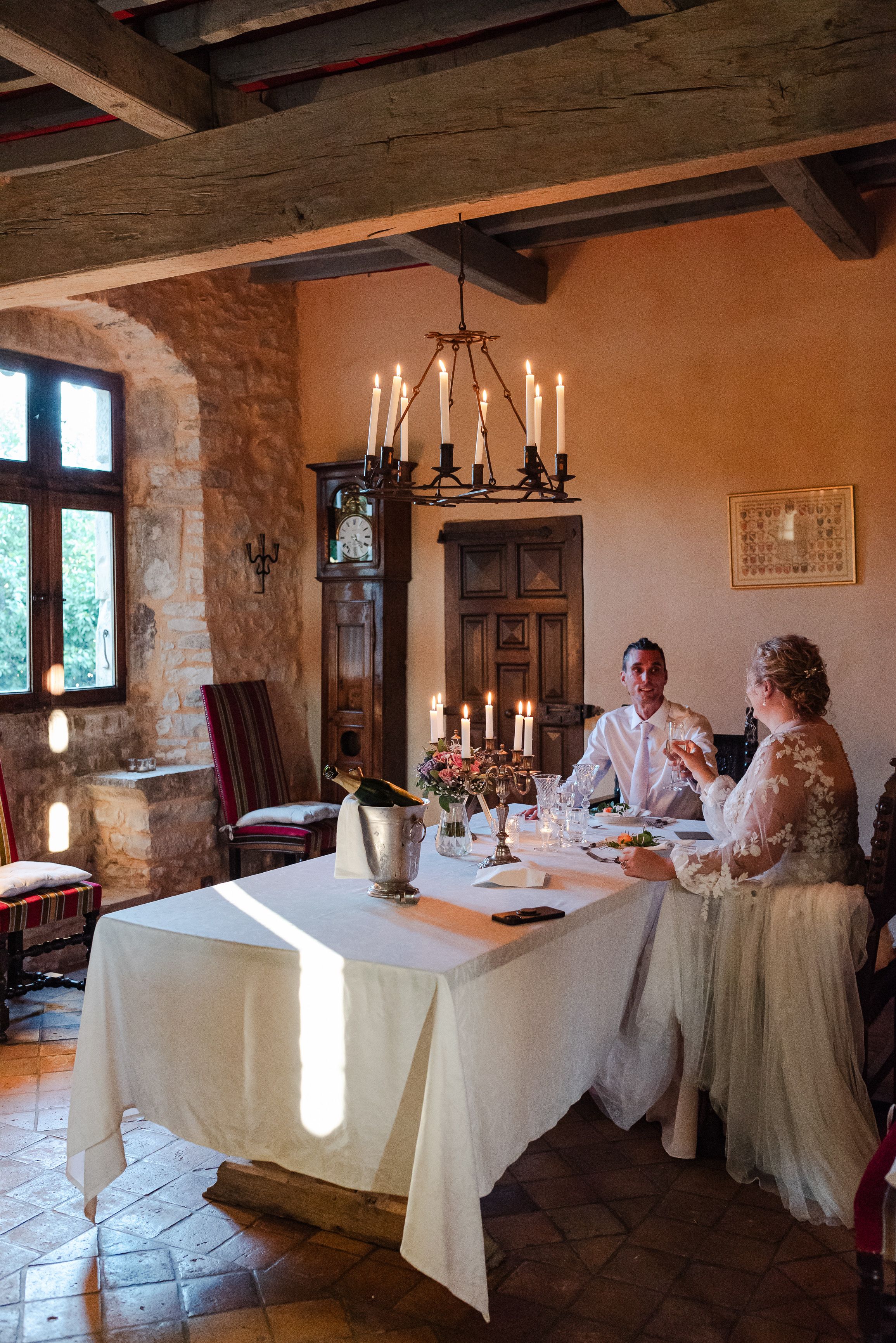 Newlyweds dining by candlelight inside a rustic stone venue during a small wedding in France