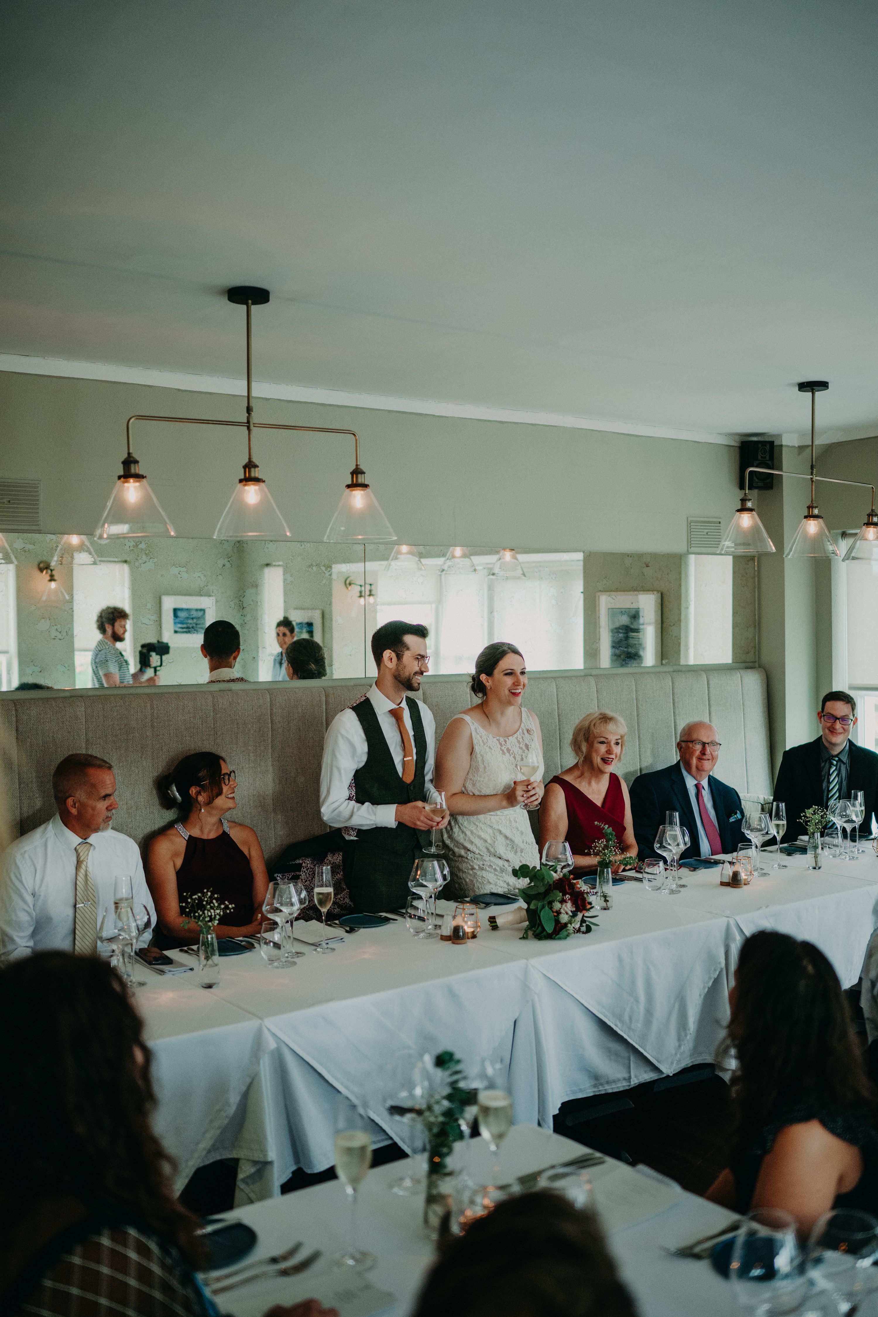 Bride and groom standing, with guests seated beside them inside an event room during their destination wedding in Ireland