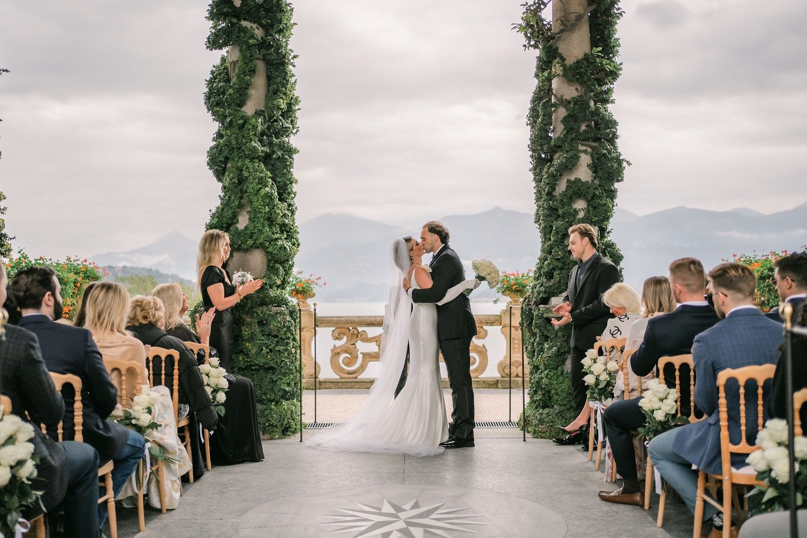 A bride and groom kissing with their family and friends watching during their small wedding in Italy