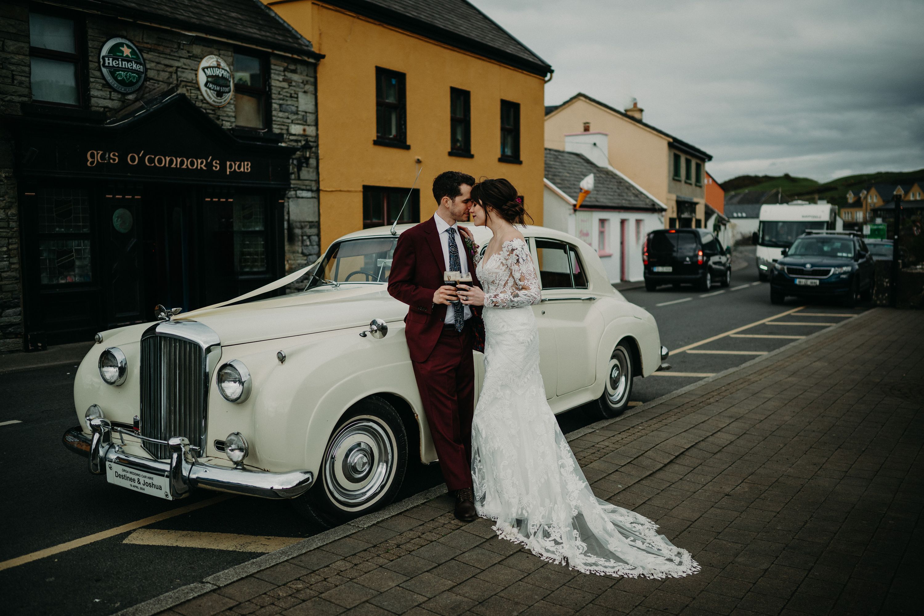 A bride and groom standing beside a classy white car after their intimate wedding in Ireland