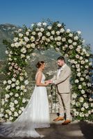 Bride and groom hold hands during the ceremony of their elopement in Italy atop a terrace with views of Amalfi