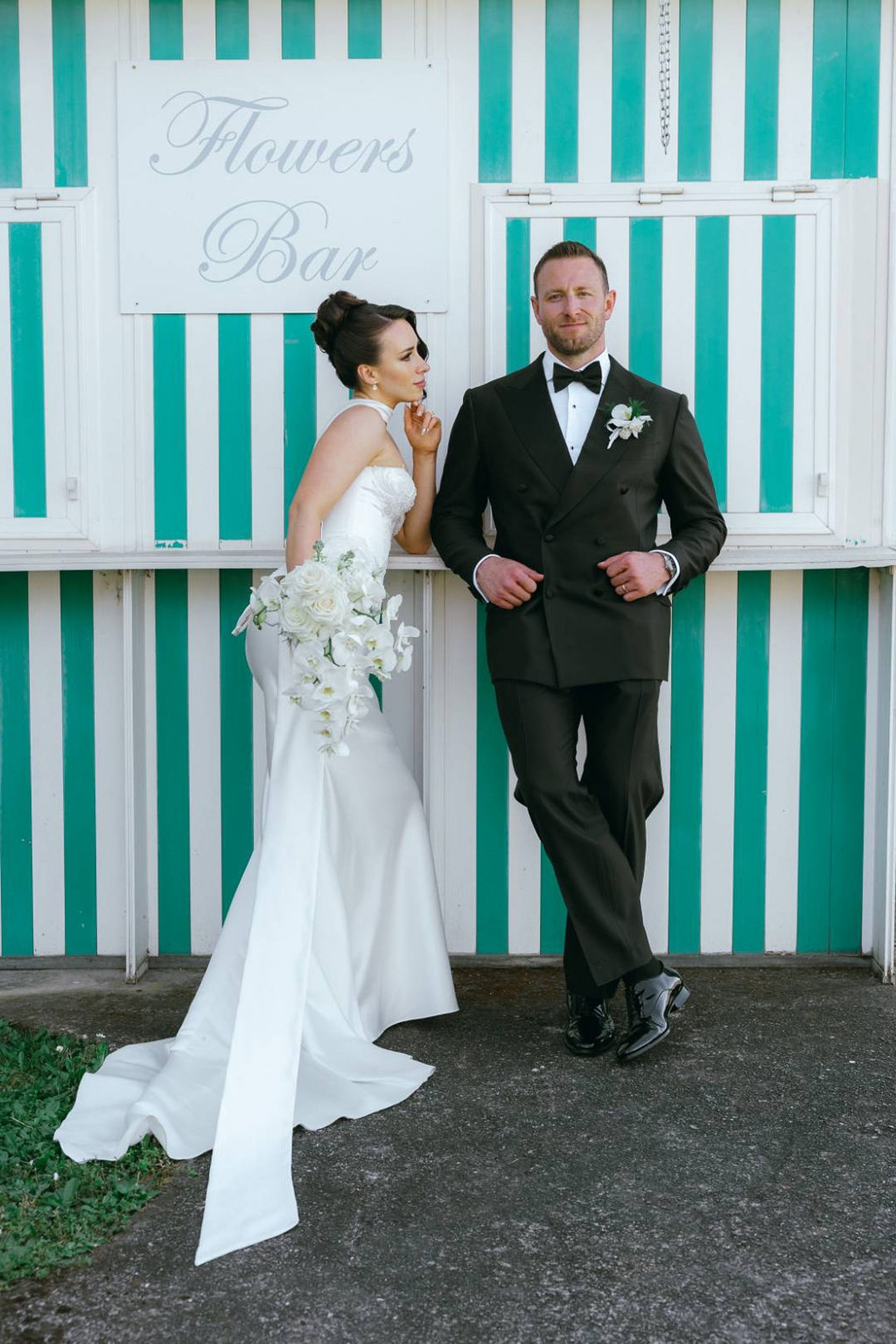 Bride and groom posing by a striped flower bar backdrop at an intimate wedding in Italy