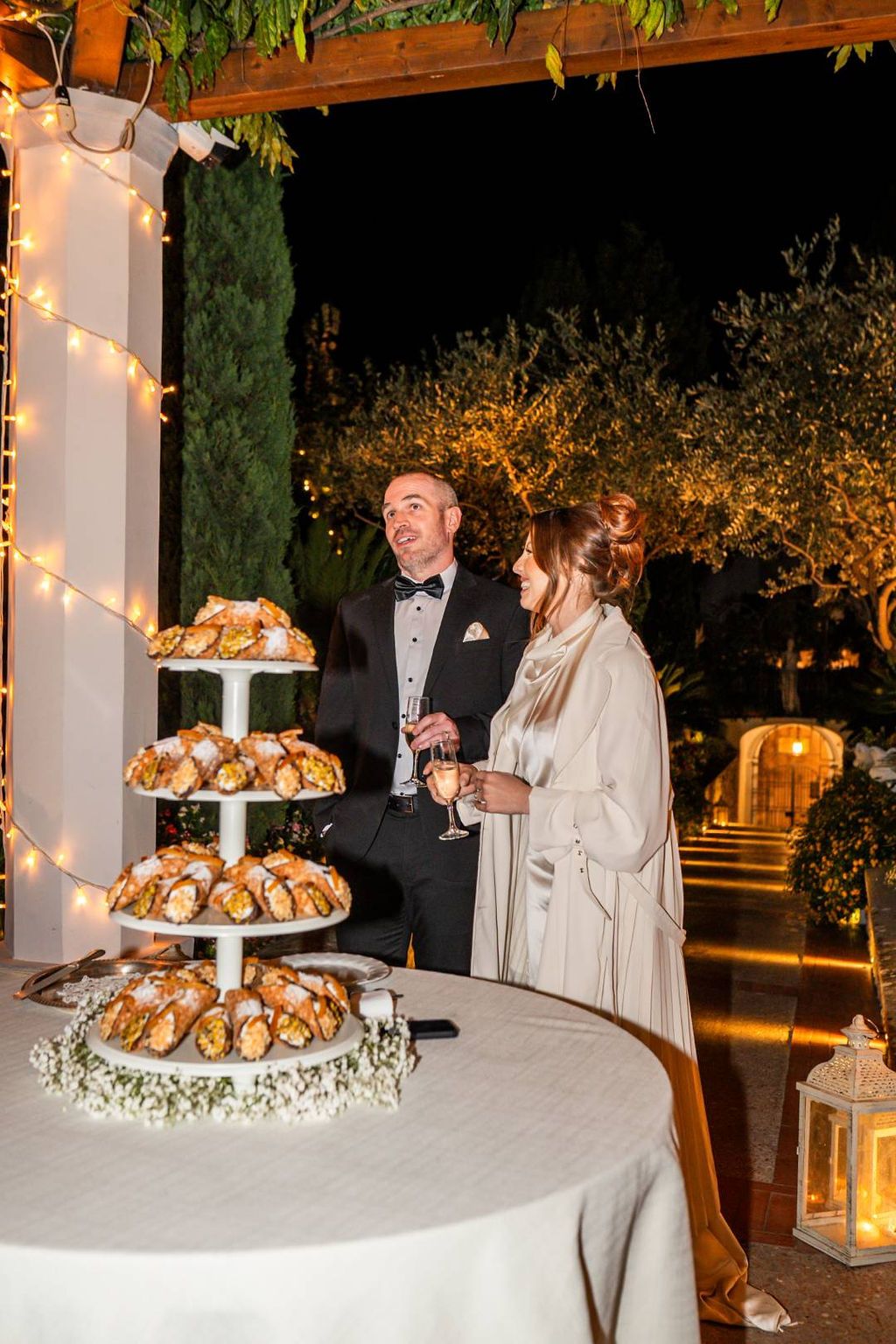 Newlyweds make a speech in front of their non-traditional wedding cake and their guests when they renewed vows in Italy
