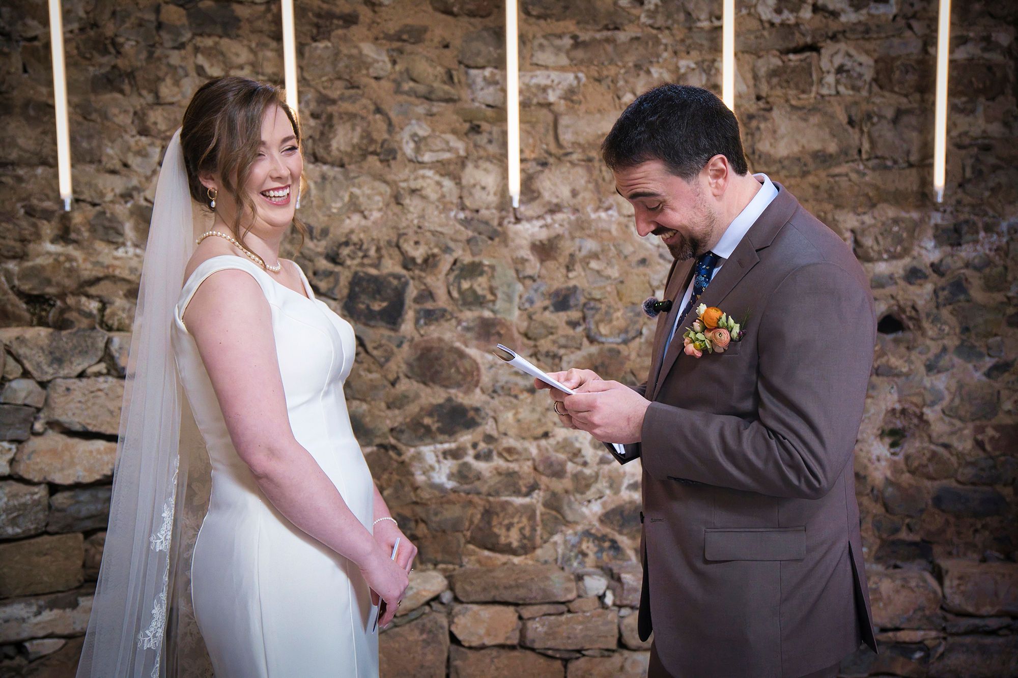 Bride smiles as groom recites vow in an indoor wedding ceremony in Spain