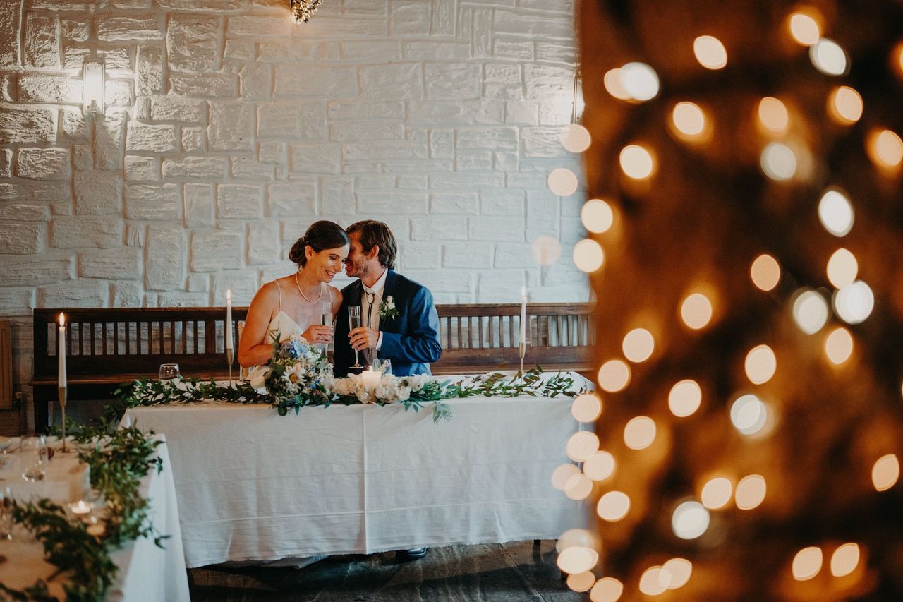 Groom whispers on his bride’s ears while they are sitting down during the reception of their destination wedding in Ireland