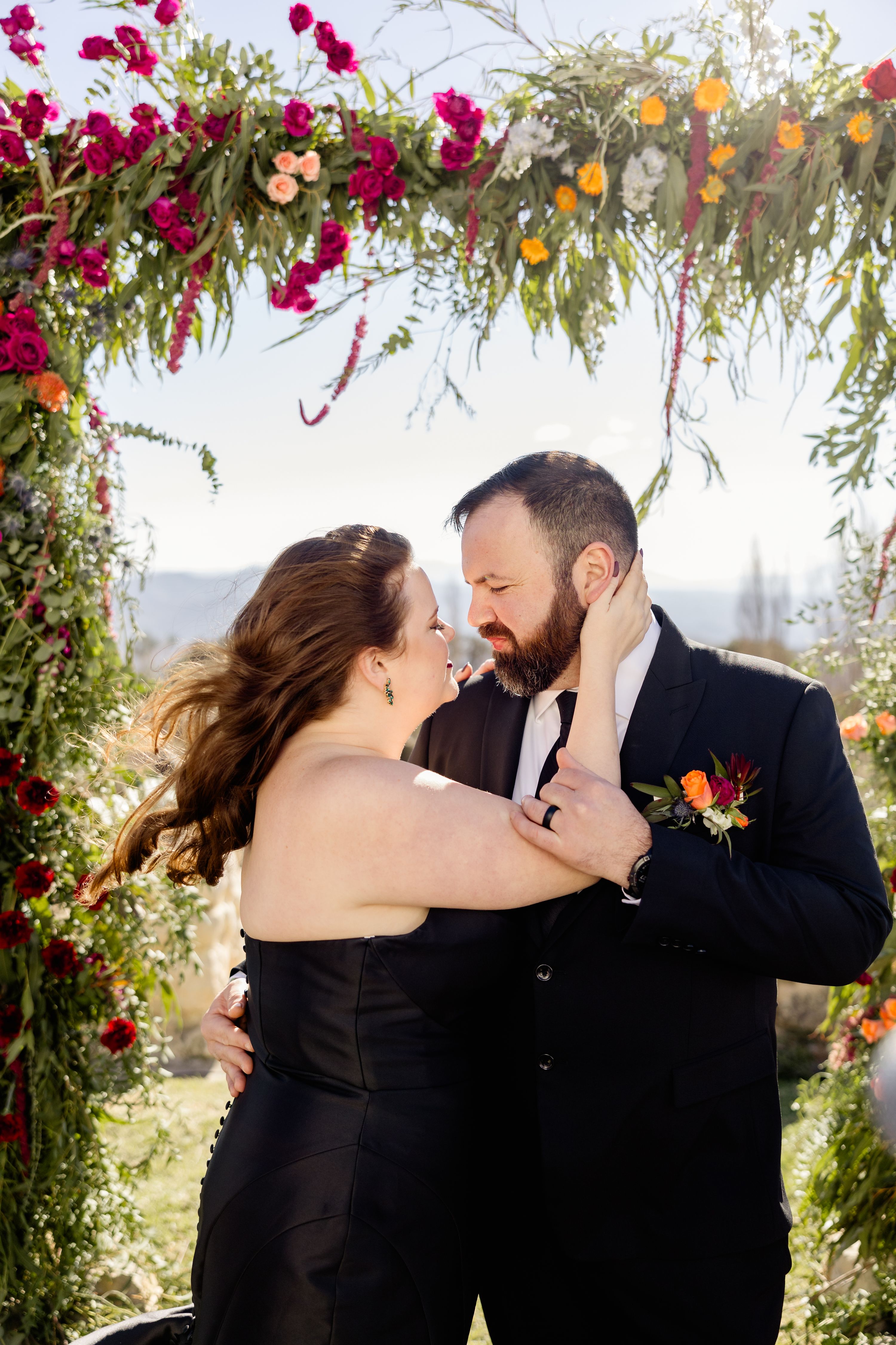 Newlyweds about to kiss during their destination wedding in Spain outdoors with a floral arch in the background