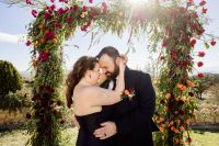 Bride and groom posing under a floral arch at their destination wedding in Spain