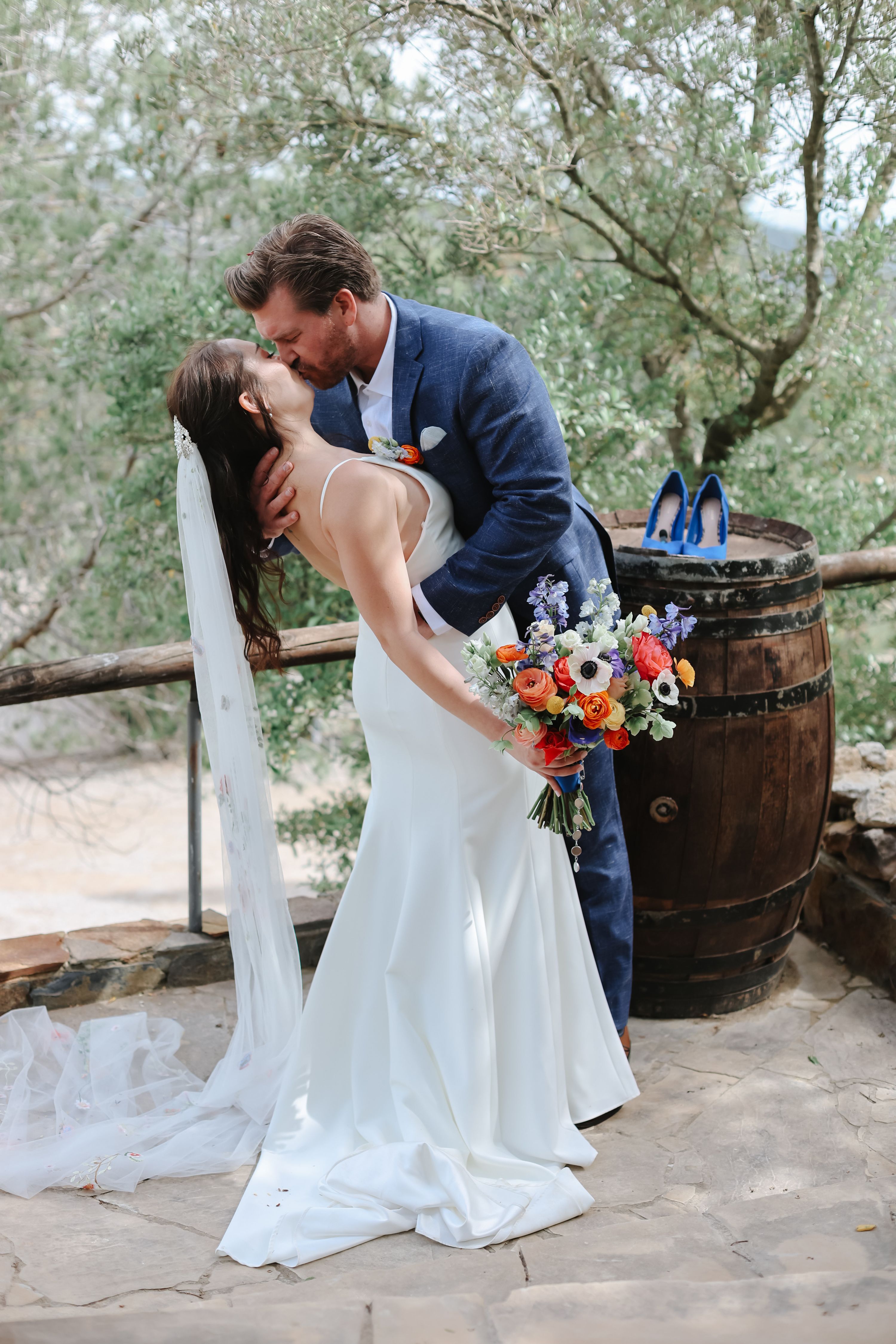 Groom kissing his bride under an olive tree at a destination wedding in spain