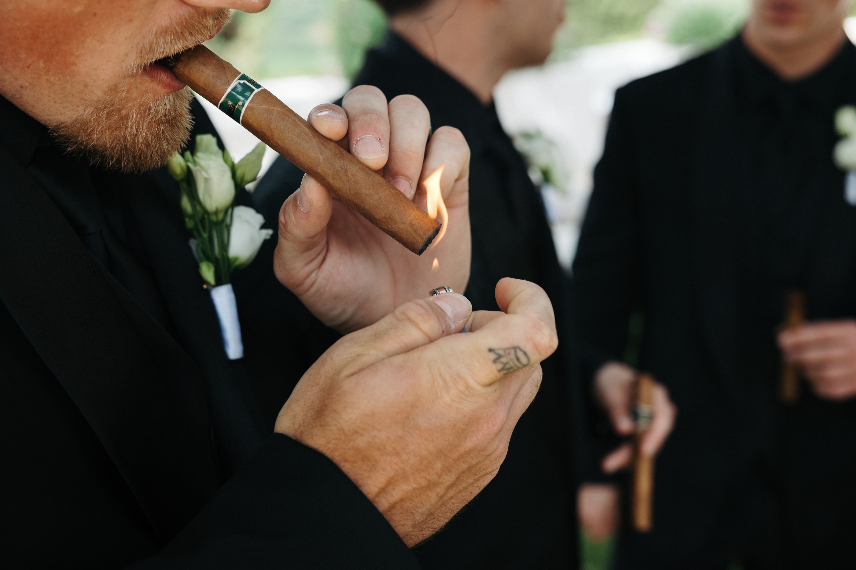 Closeup of wedding guests lighting a cigar before the wedding ceremony