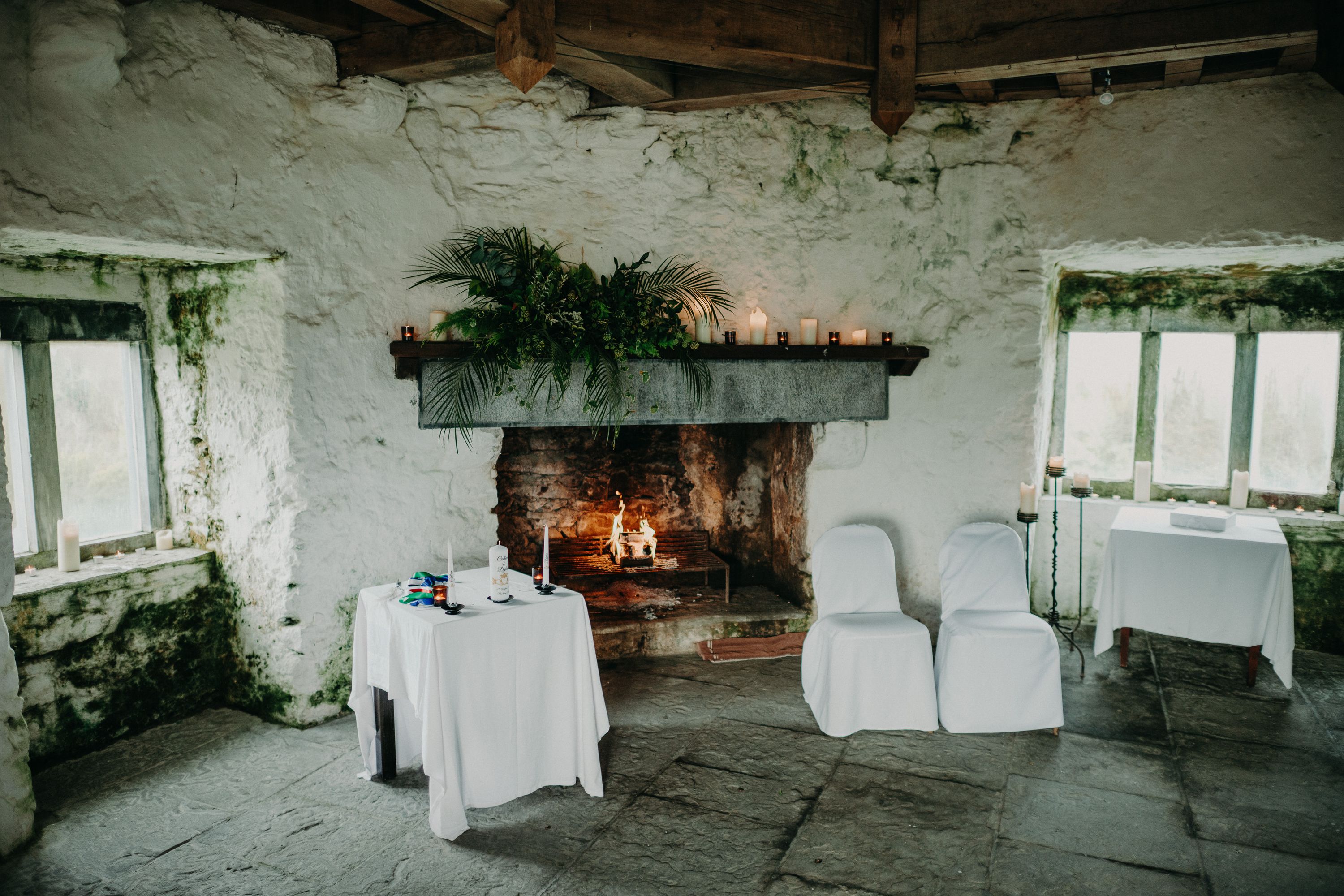 Rustic stone ceremony room with fireplace prepared for a small wedding in Ireland at a historic castle.