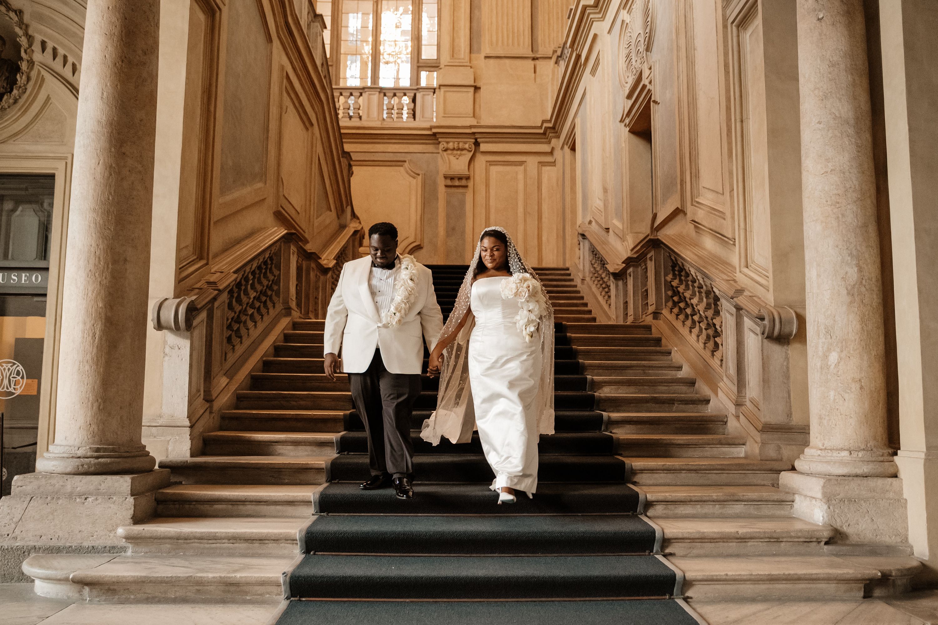 Newlyweds going down the stairs of a museum in Turin after the ceremony of their elopement in Italy