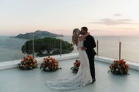 Bride and groom kiss under the sunset atop a hotel terrace in Sorrento during their small wedding in Italy