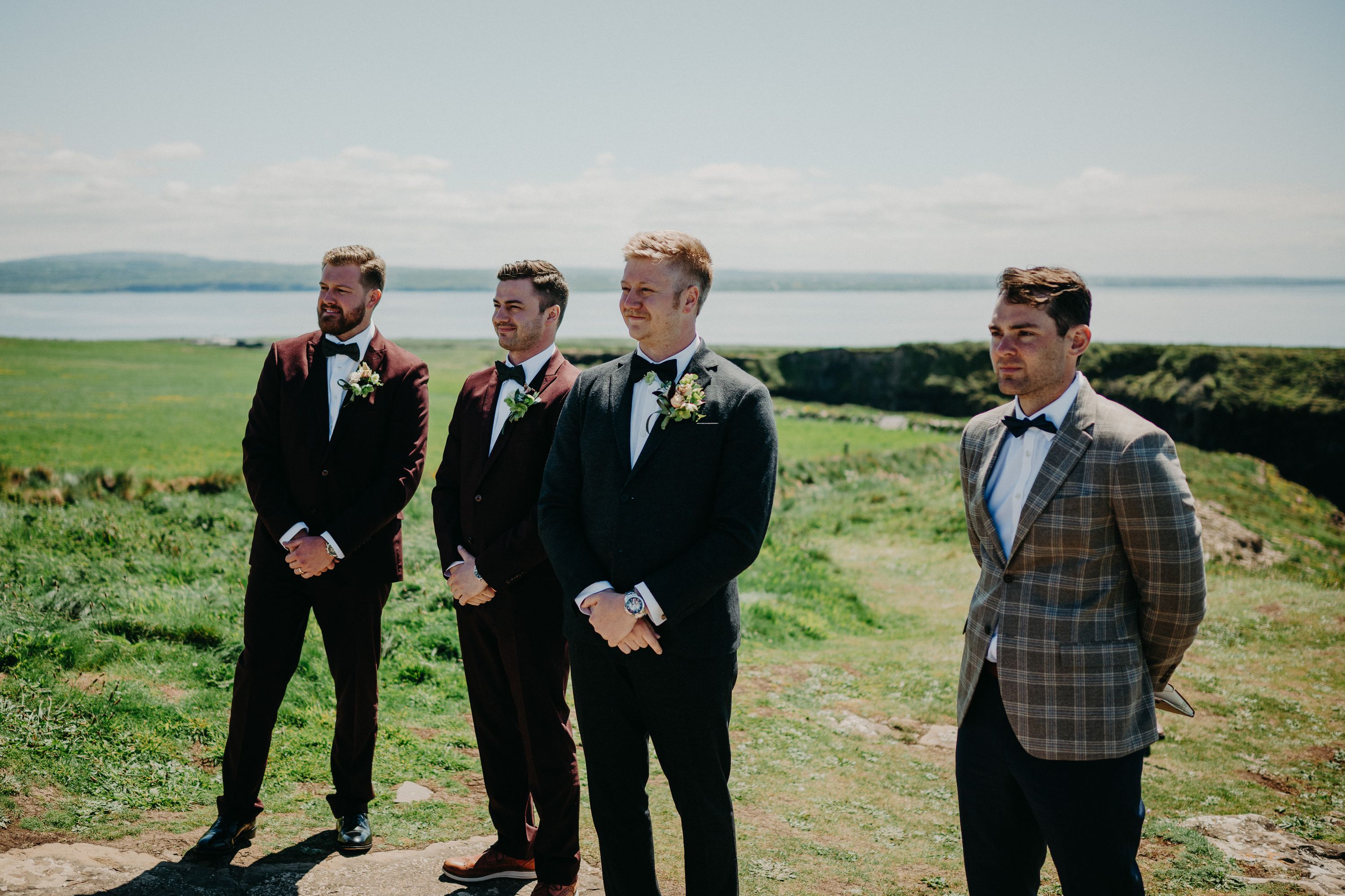 A groom and his groomsmen standing on a beautiful cliff while waiting for a bride during their intimate wedding in Ireland
