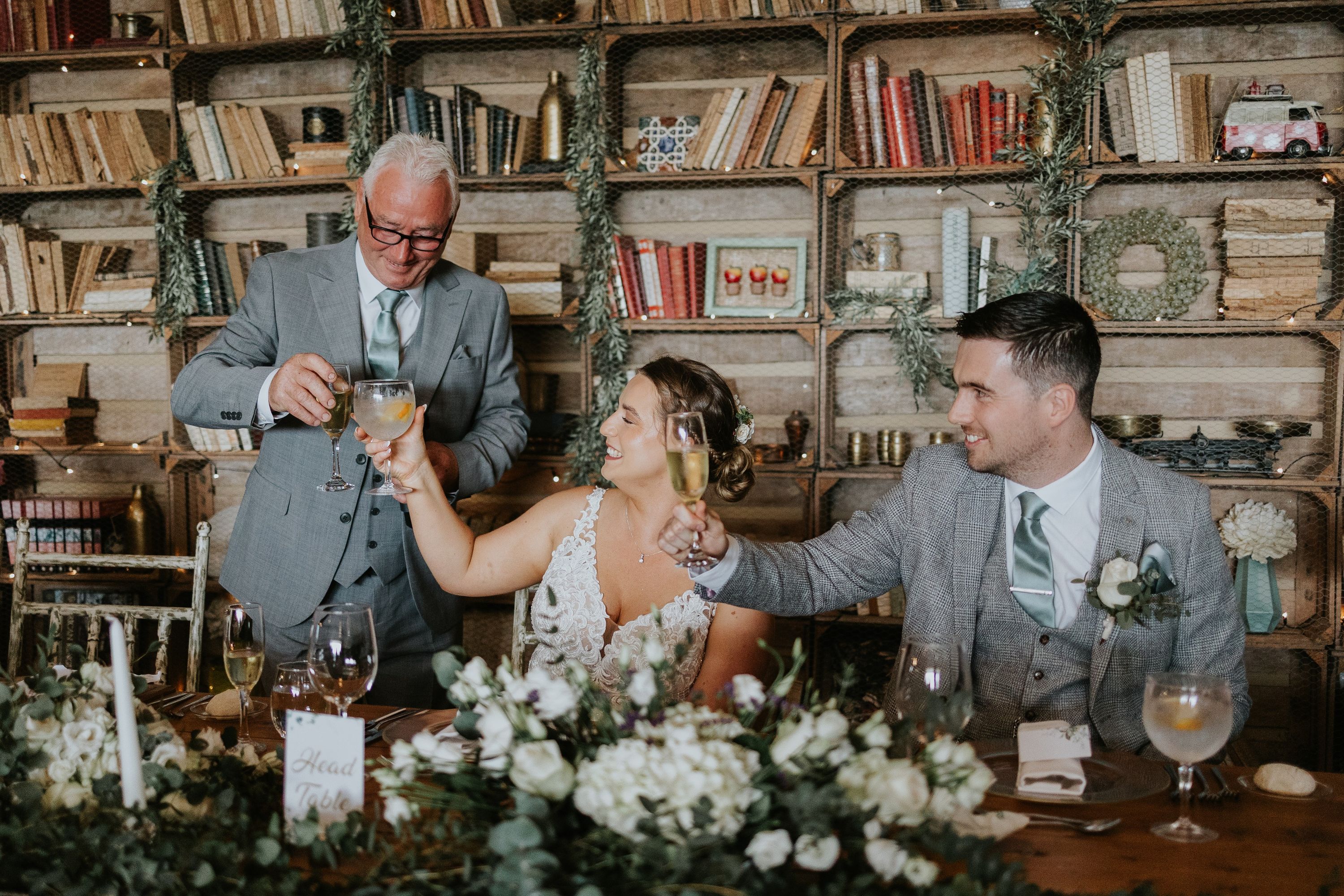 Bride and groom raise their glasses to receive drinks from an elderly guest during their wedding reception in Portugal