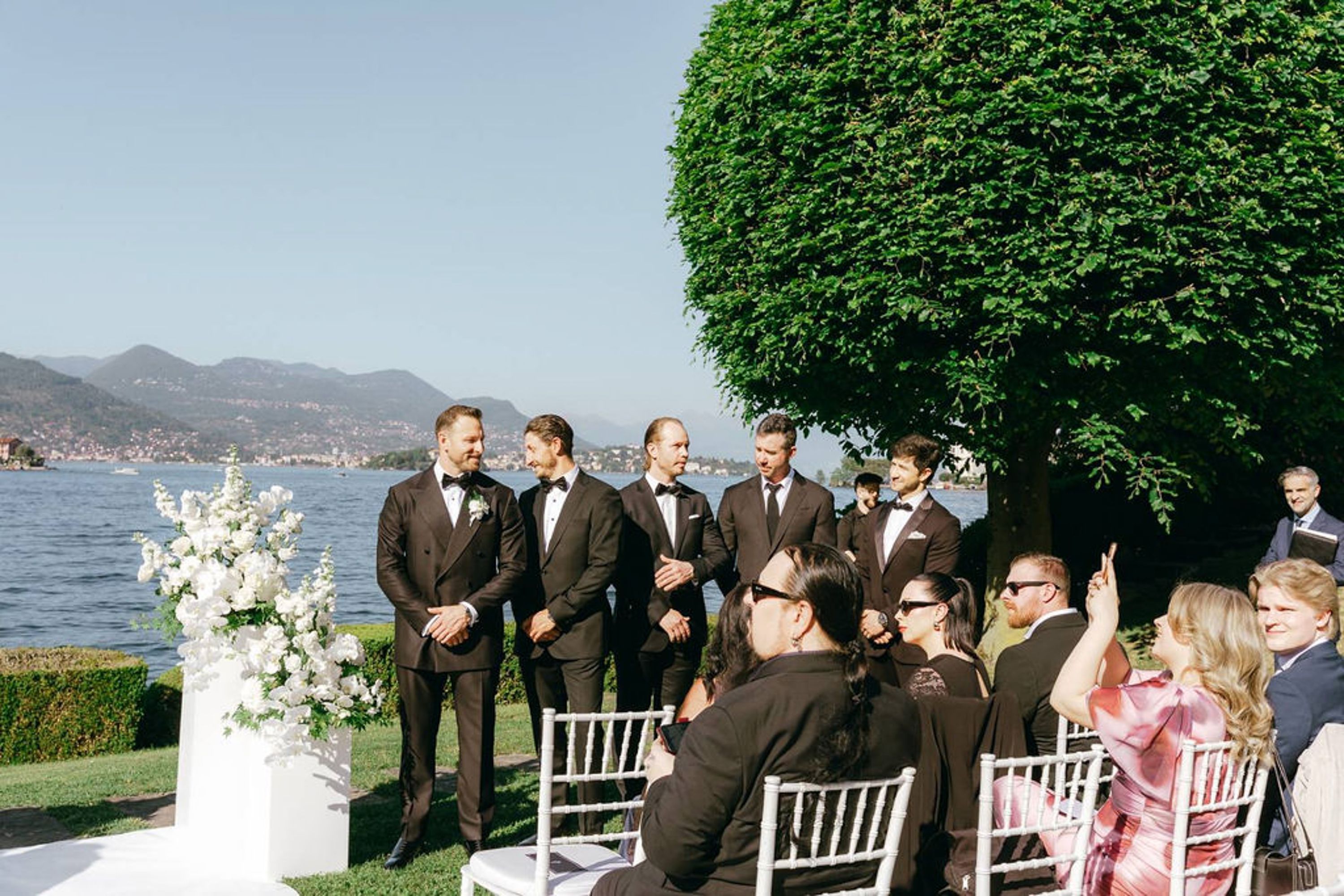 Guests and groomsmen gathered for a lakeside ceremony during a small wedding in Italy
