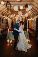 Bride and groom looking at each other while hugging with ceiling ball decor at the pub where they had a wedding reception