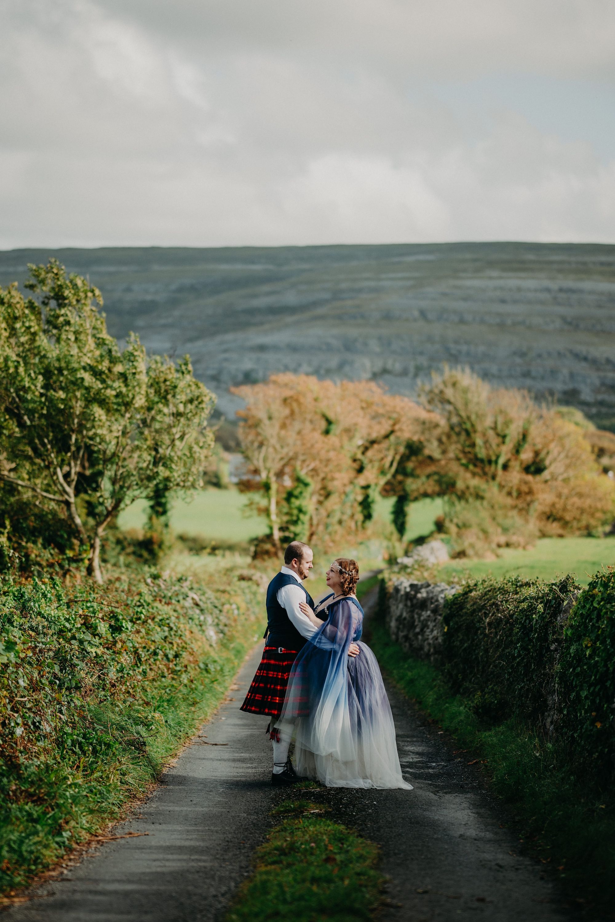 Newlyweds hold each other with Irish trees and hills of Clare in the background when they eloped in Ireland