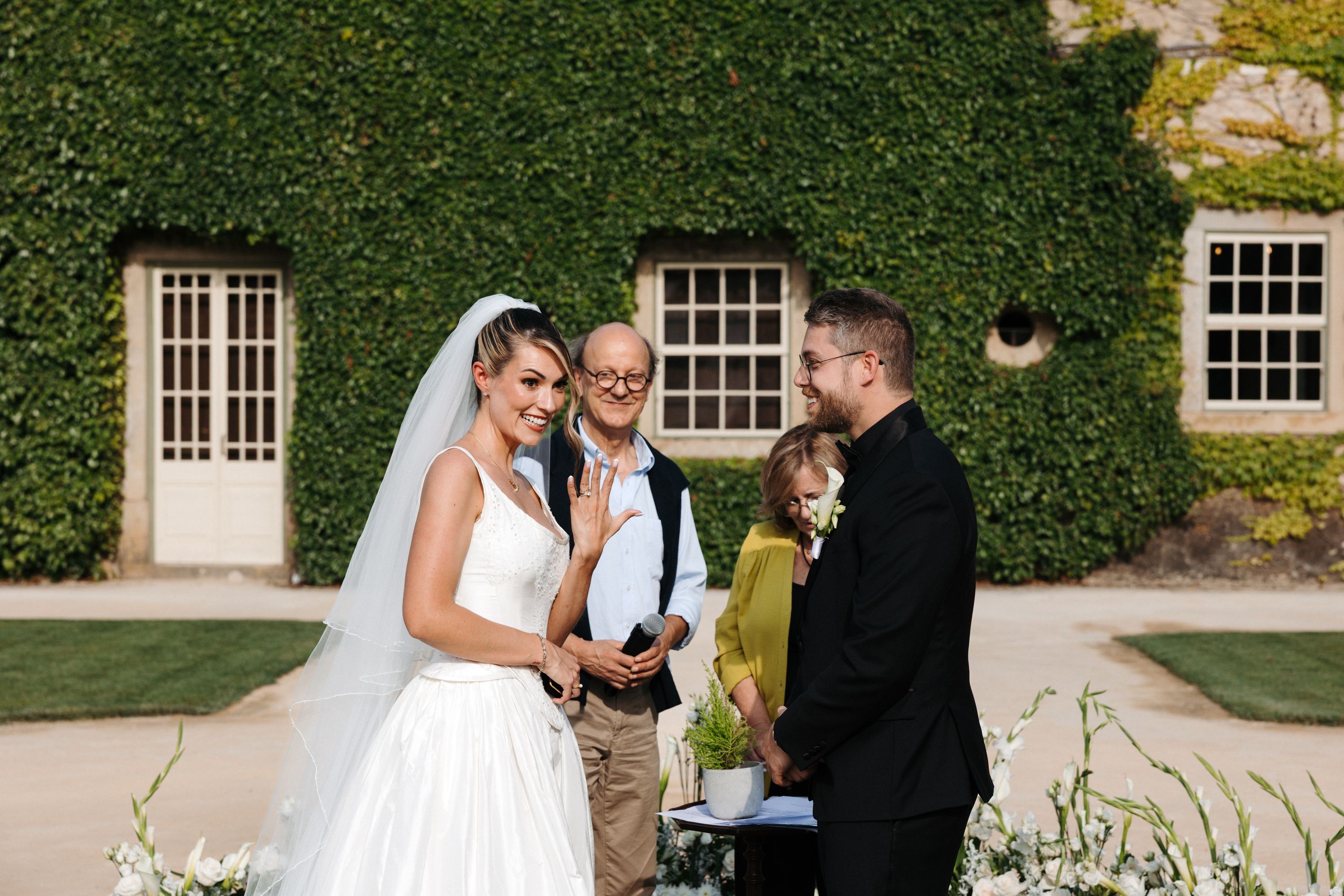 Bride smiles to their guests as she shows her ring during the outdoor ceremony of their destination wedding in Portugal