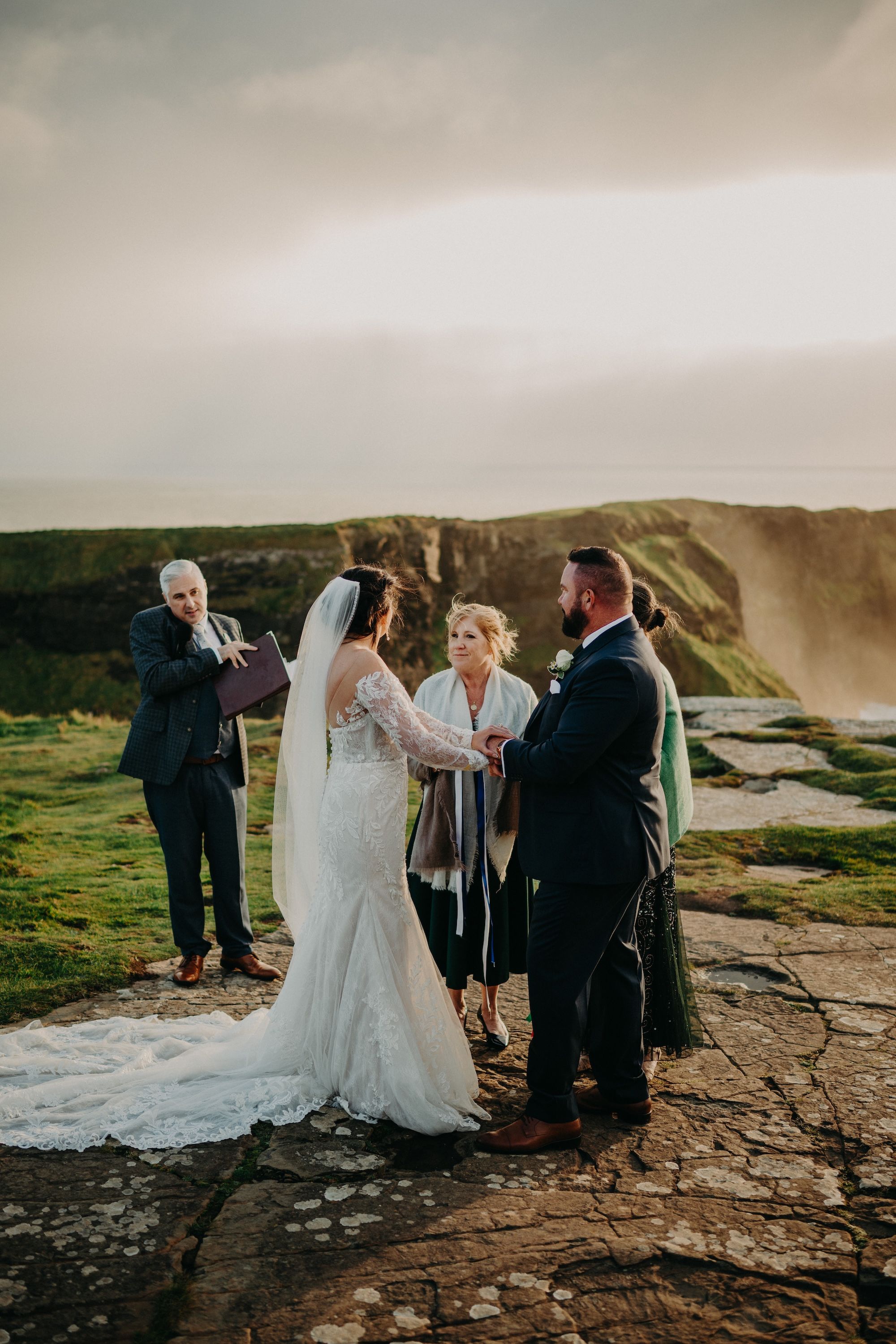 Bride and groom holding each other's hands during the clifftop ceremony of their small wedding in Ireland