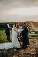 Bride and groom holding each other's hands during the clifftop ceremony of their small wedding in Ireland