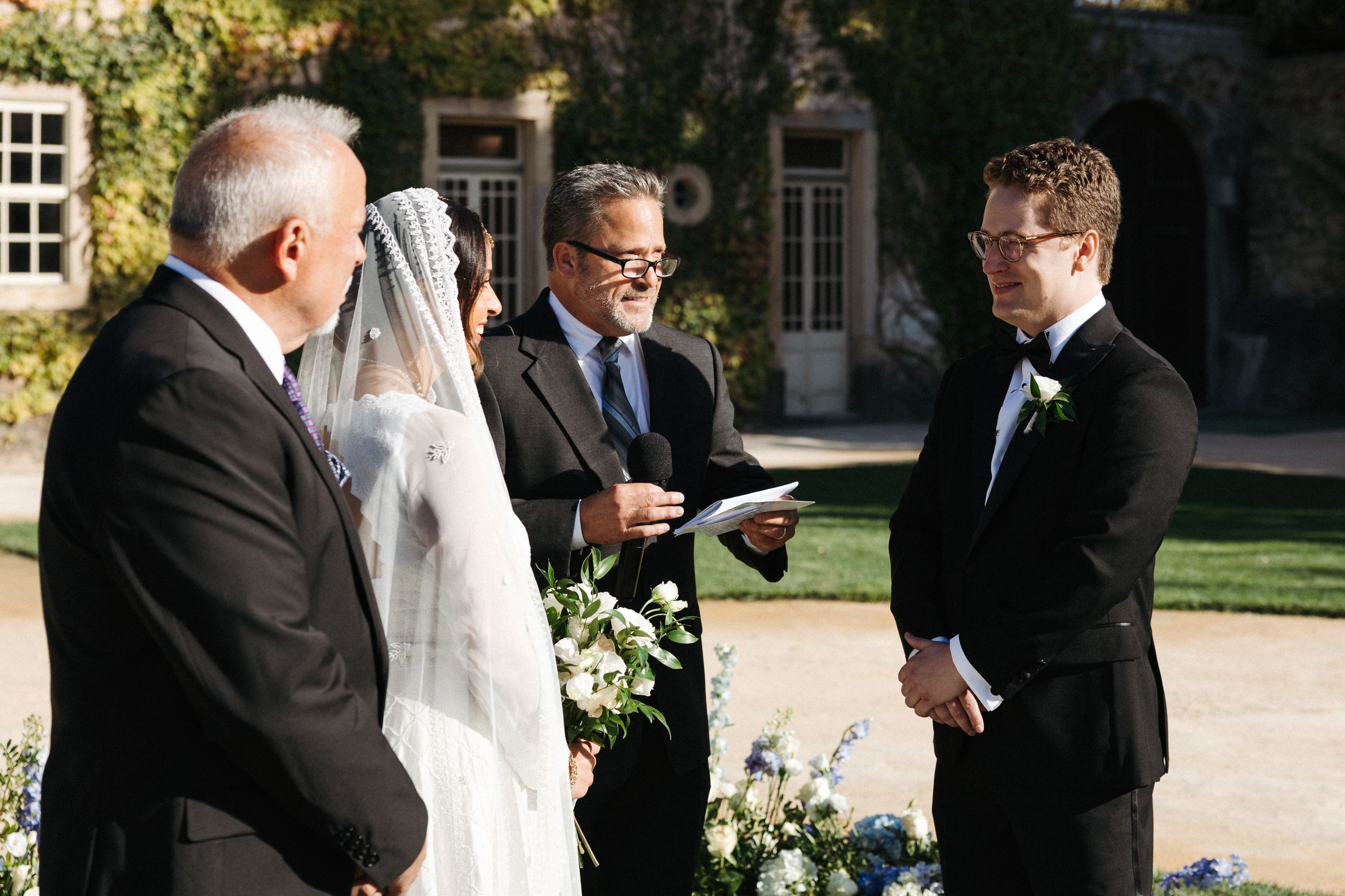 Groom listening during a garden ceremony at an intimate wedding in Portugal with family and friends present