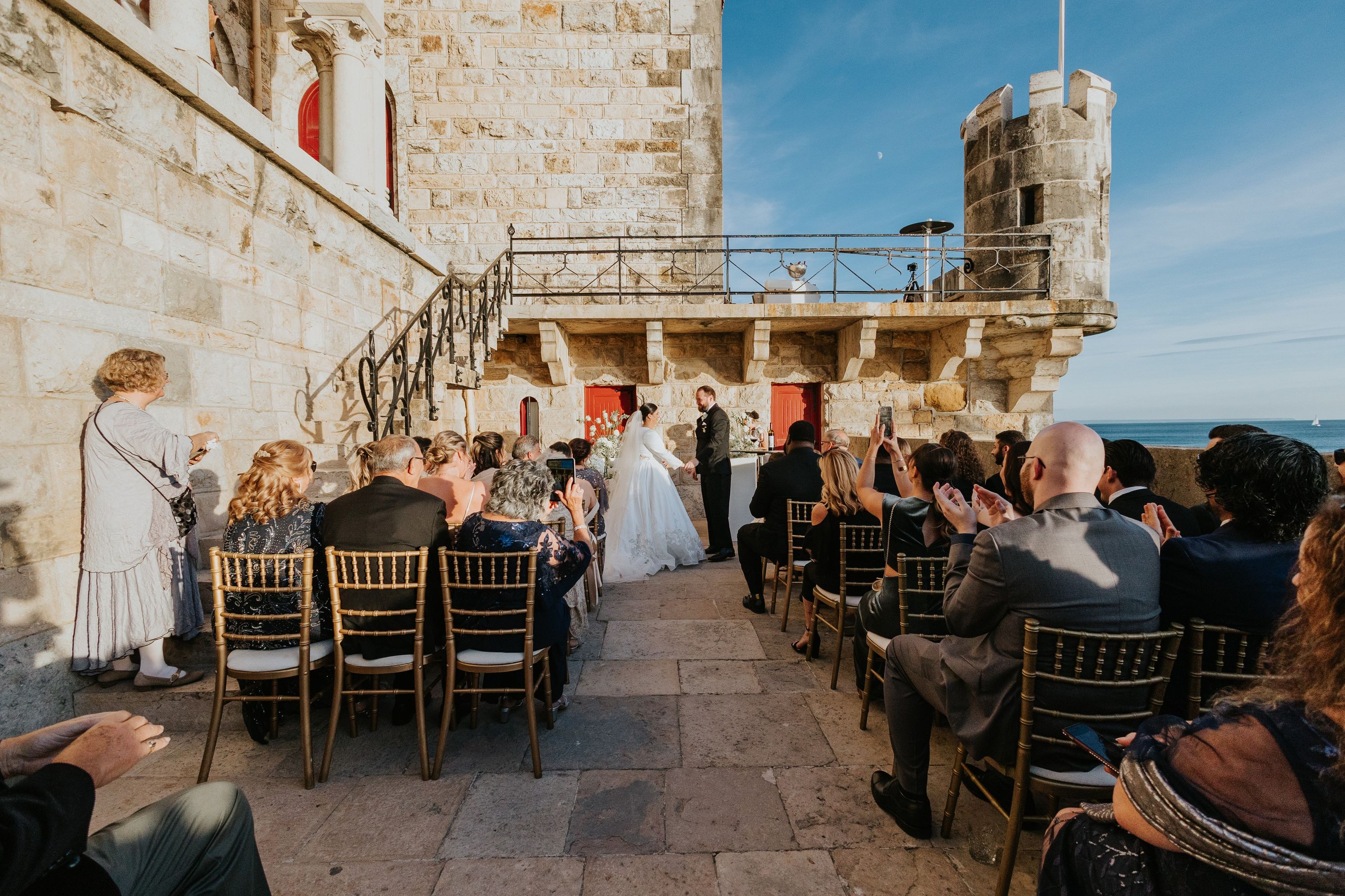 Couple with guests in a wedding ceremony atop a castle's terrace in Portugal