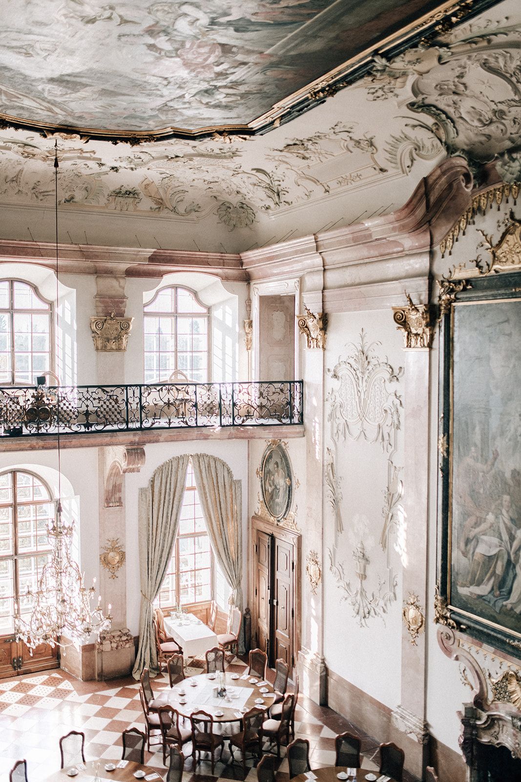 Frescoed baroque ballroom set with round dinner tables for a palace wedding in Austria