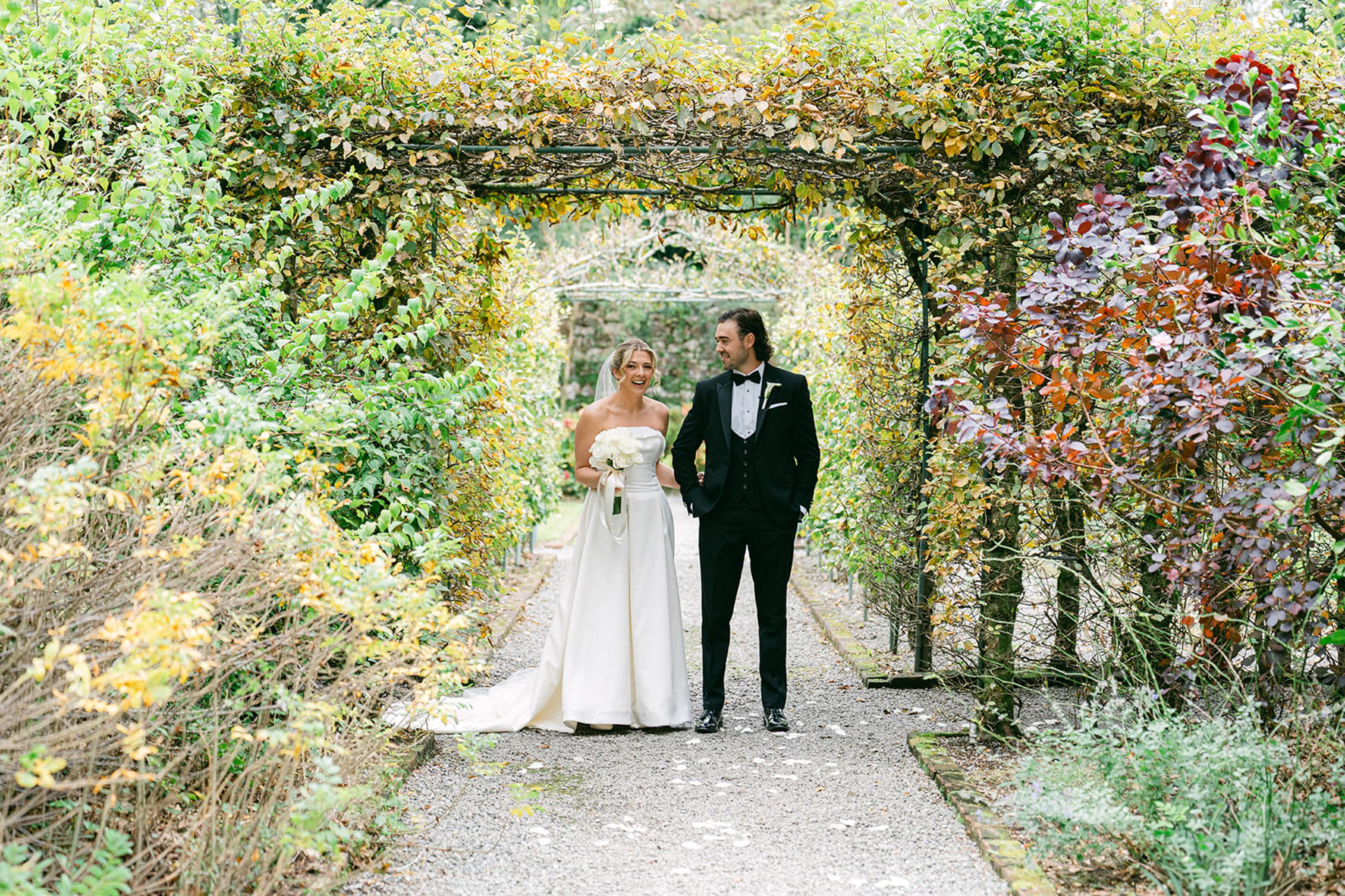 Newlyweds walking through a lush garden archway after an intimate wedding in Europe