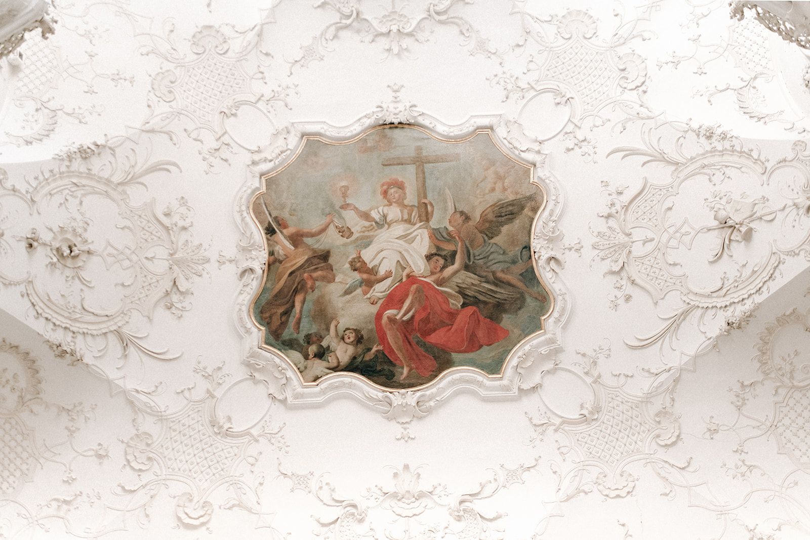 Rococo ceiling fresco framed by white stucco in an Austrian palace hall