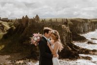 Newlyweds on top of Antrim’s cliffs hugging each other on a windy day when they got married in Northern Ireland