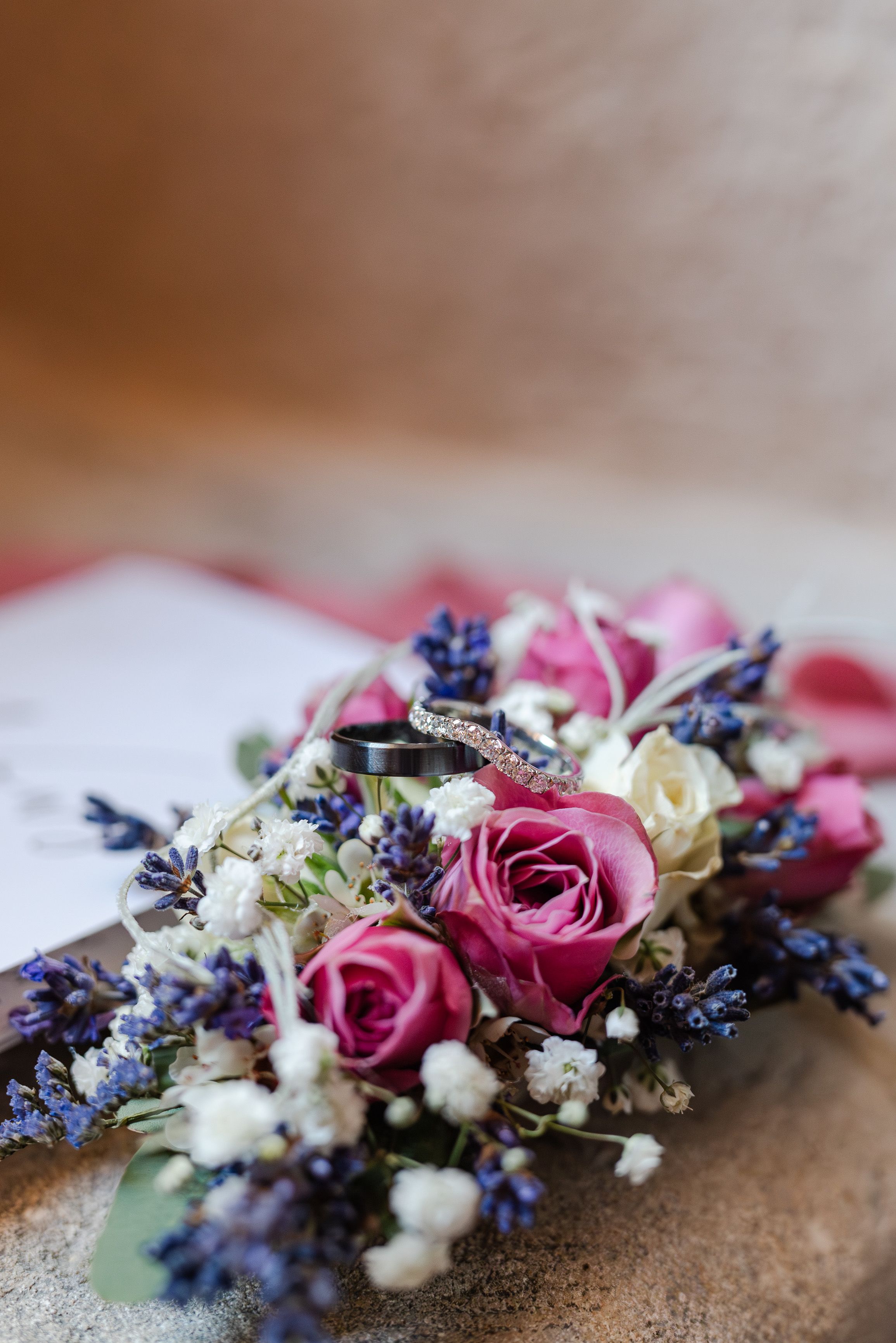 Wedding rings displayed on a lavender and rose bouquet at an intimate wedding in France