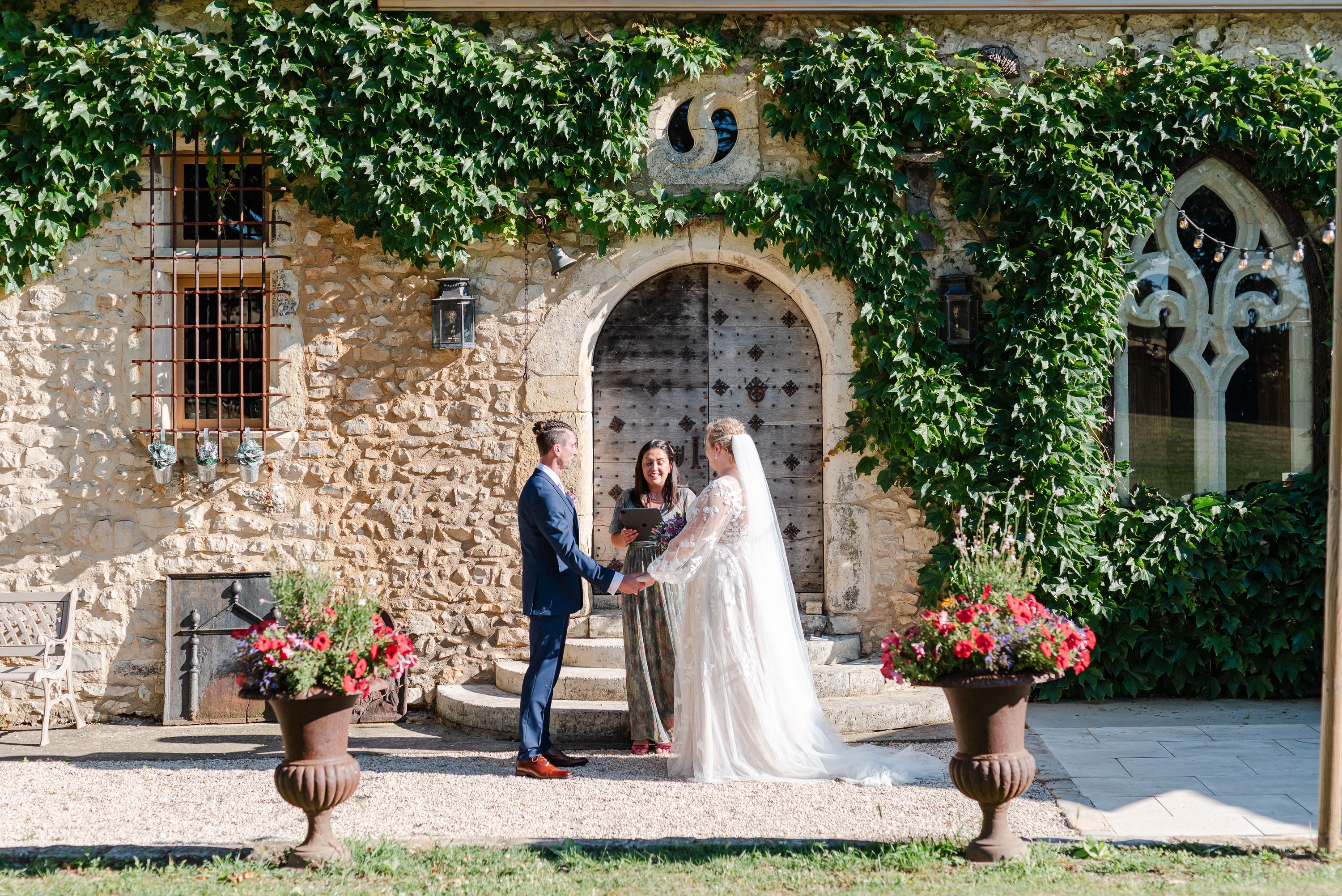 Couple exchanging vows outside a stone manor during a small wedding in France