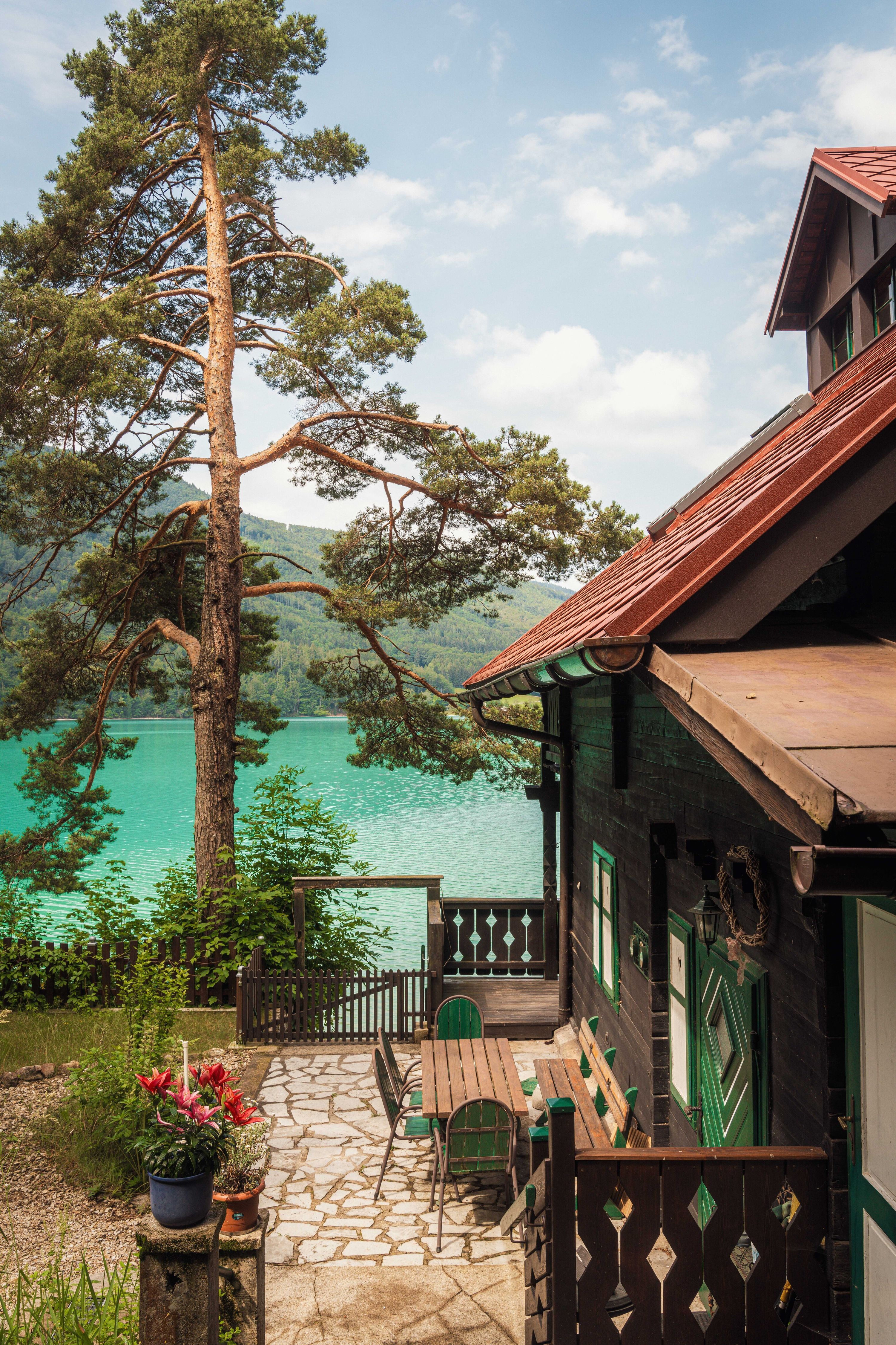 Dark-timber lakeside cabin above a turquoise Alpine lake in Austria
