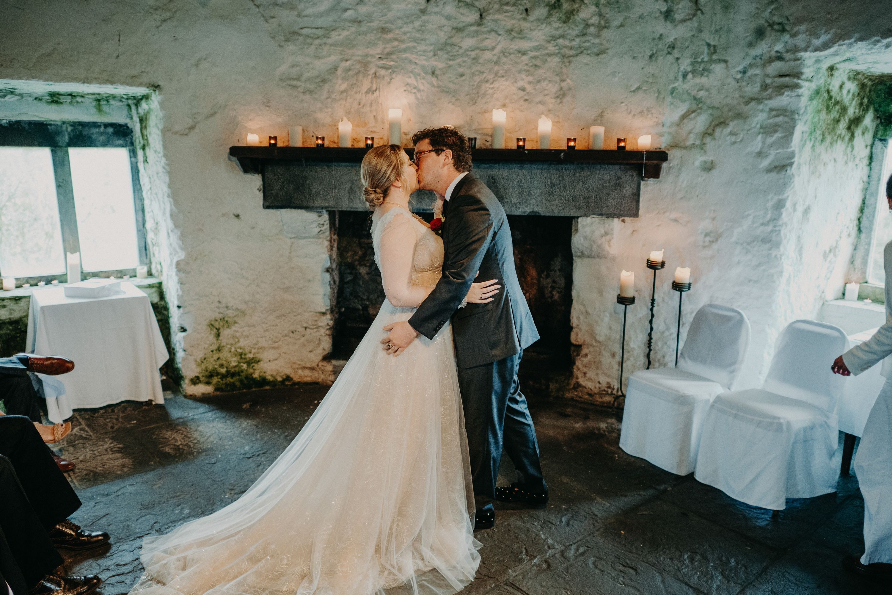 Newlyweds sharing their first kiss beside a fireplace at a small wedding in Ireland