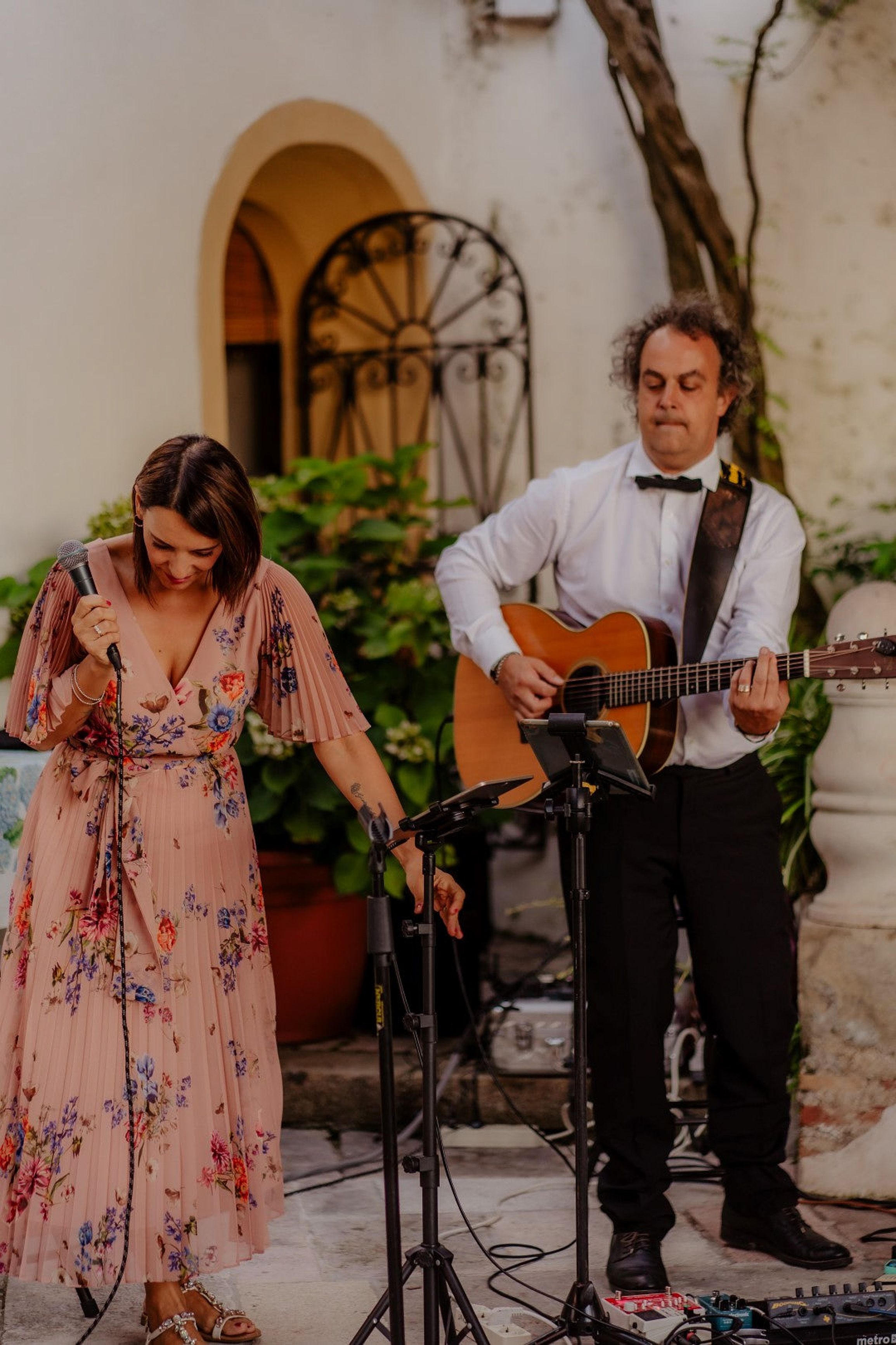 Singer and guitarist entertaining guests during an intimate wedding in Italy in a romantic courtyard setting.