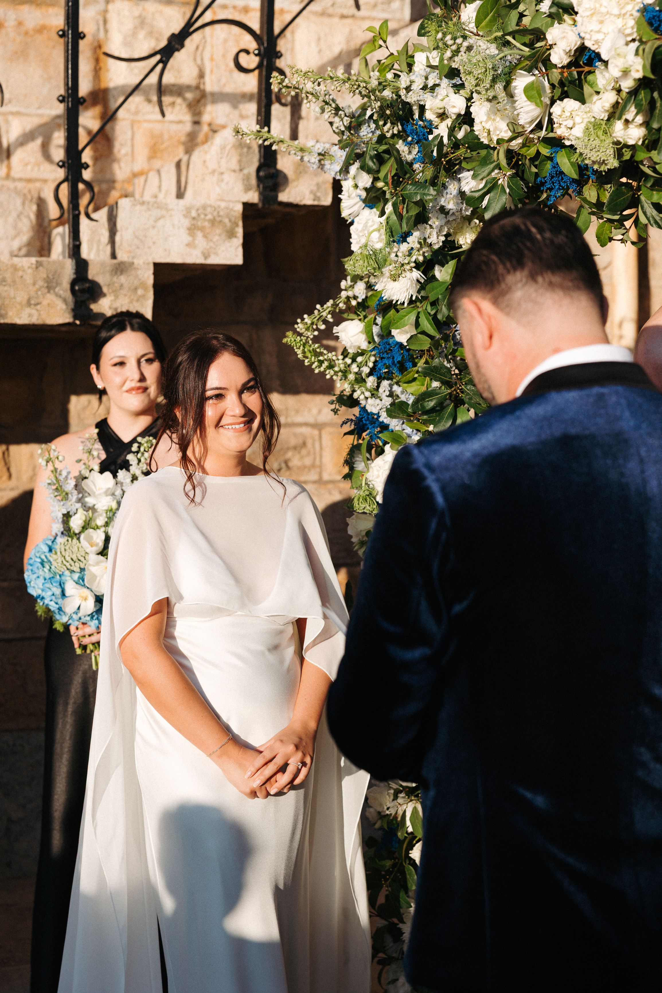 Bride smiling during heartfelt vows beneath a floral arch at a small wedding in Portugal ceremony venue
