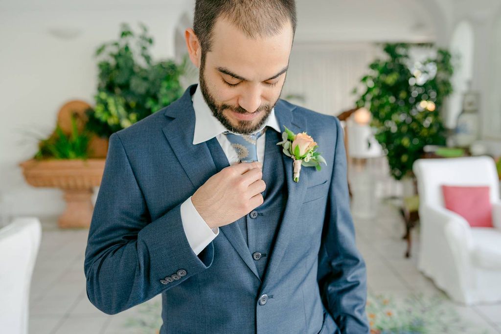 Stylish groom in a blue check suit with decorative tie accessory for an intimate wedding in Italy