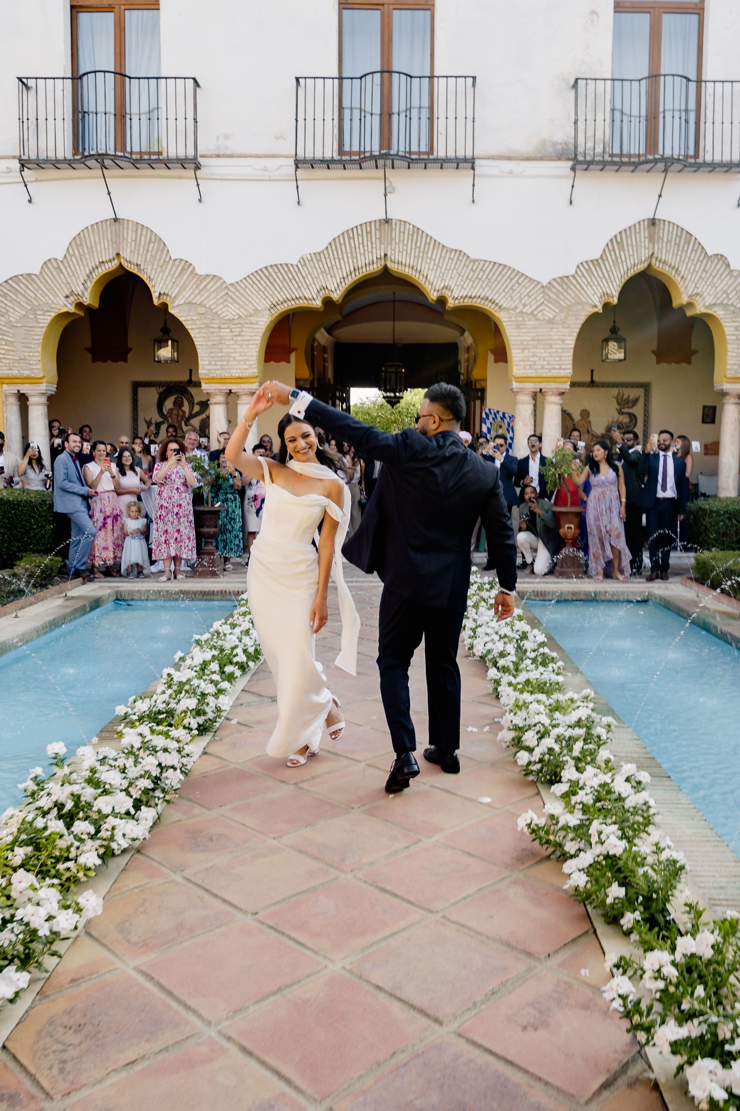 Bride and groom dance in casual attire at a farmhouse in front of their guests during their small wedding in Spain