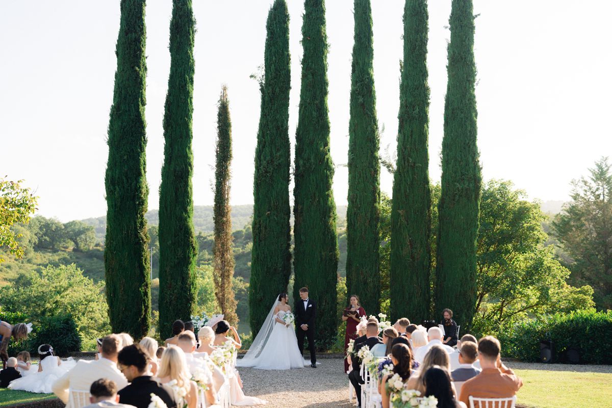 An outdoor ceremony with cypress hills and Tuscan hills in the background during a destination wedding in Tuscany