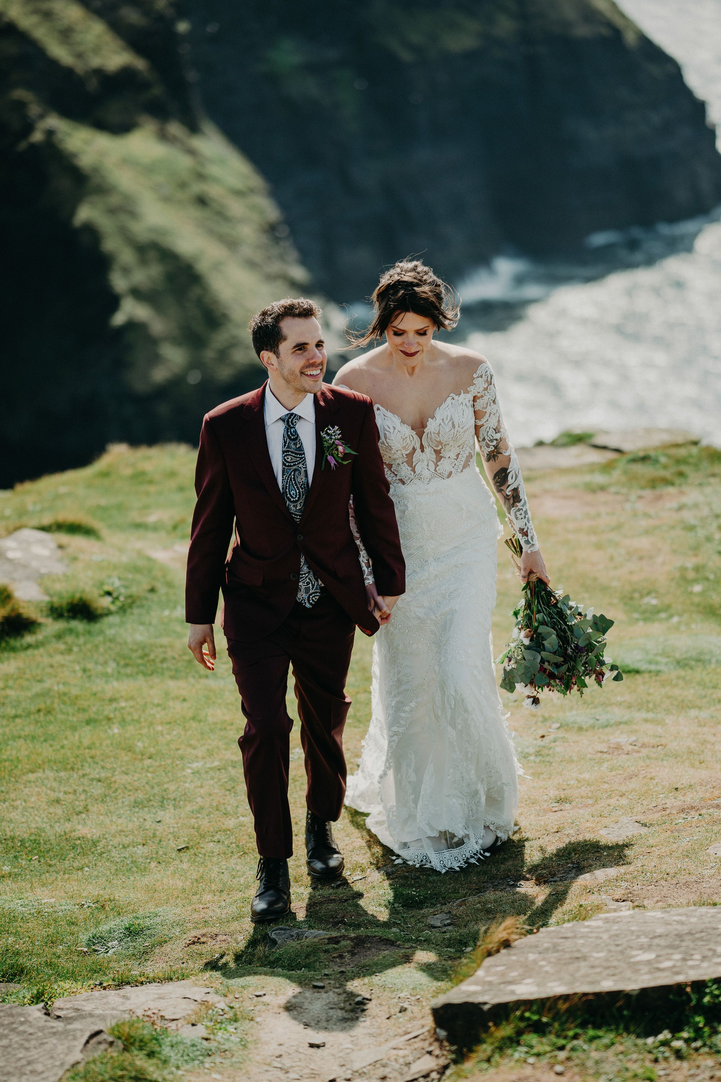 A bride and groom walking on top of a cliff after their small wedding in Ireland