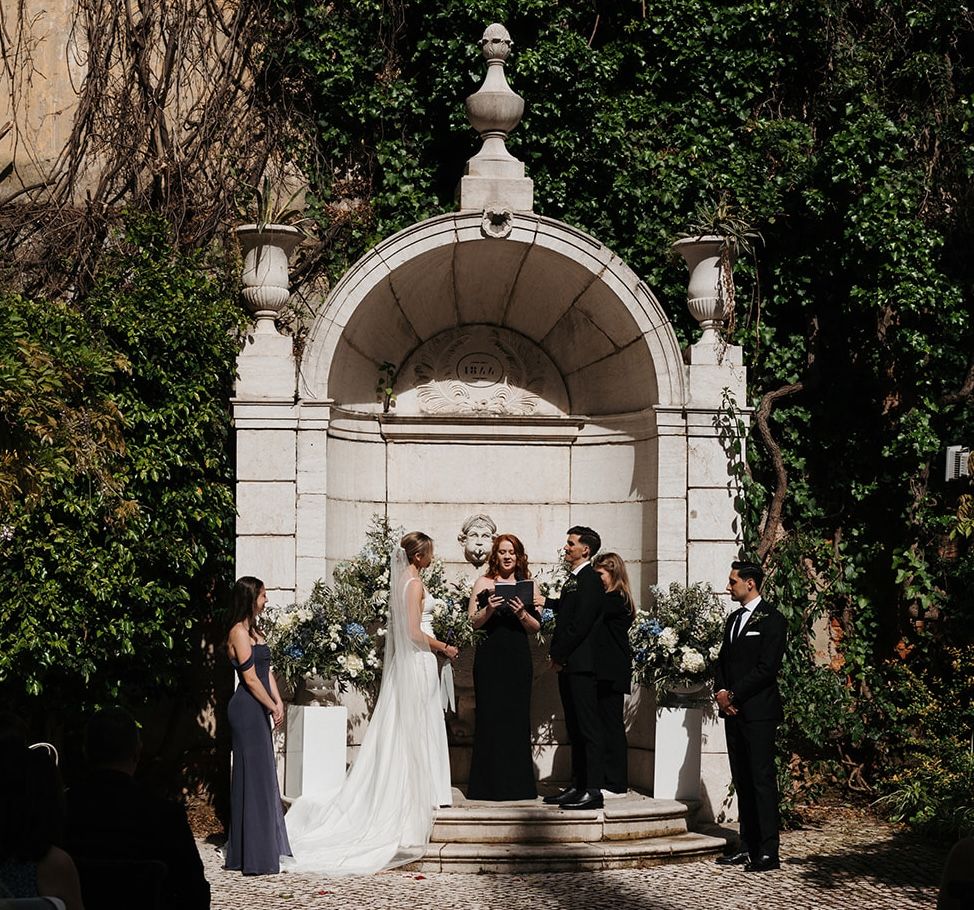 Bride and groom having an outdoor ceremony in a stone gazebo at the garden during their destination wedding in Portugal