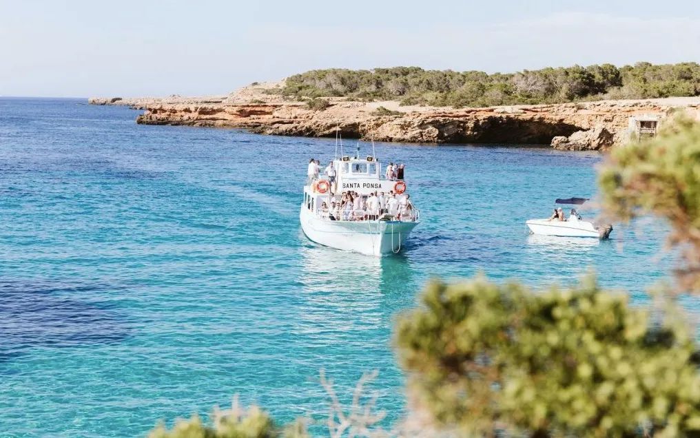 Photo of a boat sailing across the clear blue Balearic Sea near the island of Ibiza