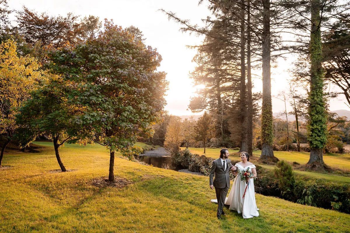 Bride and groom walking along a nature park teeming with beautiful autumn colors during their destination wedding in Ireland