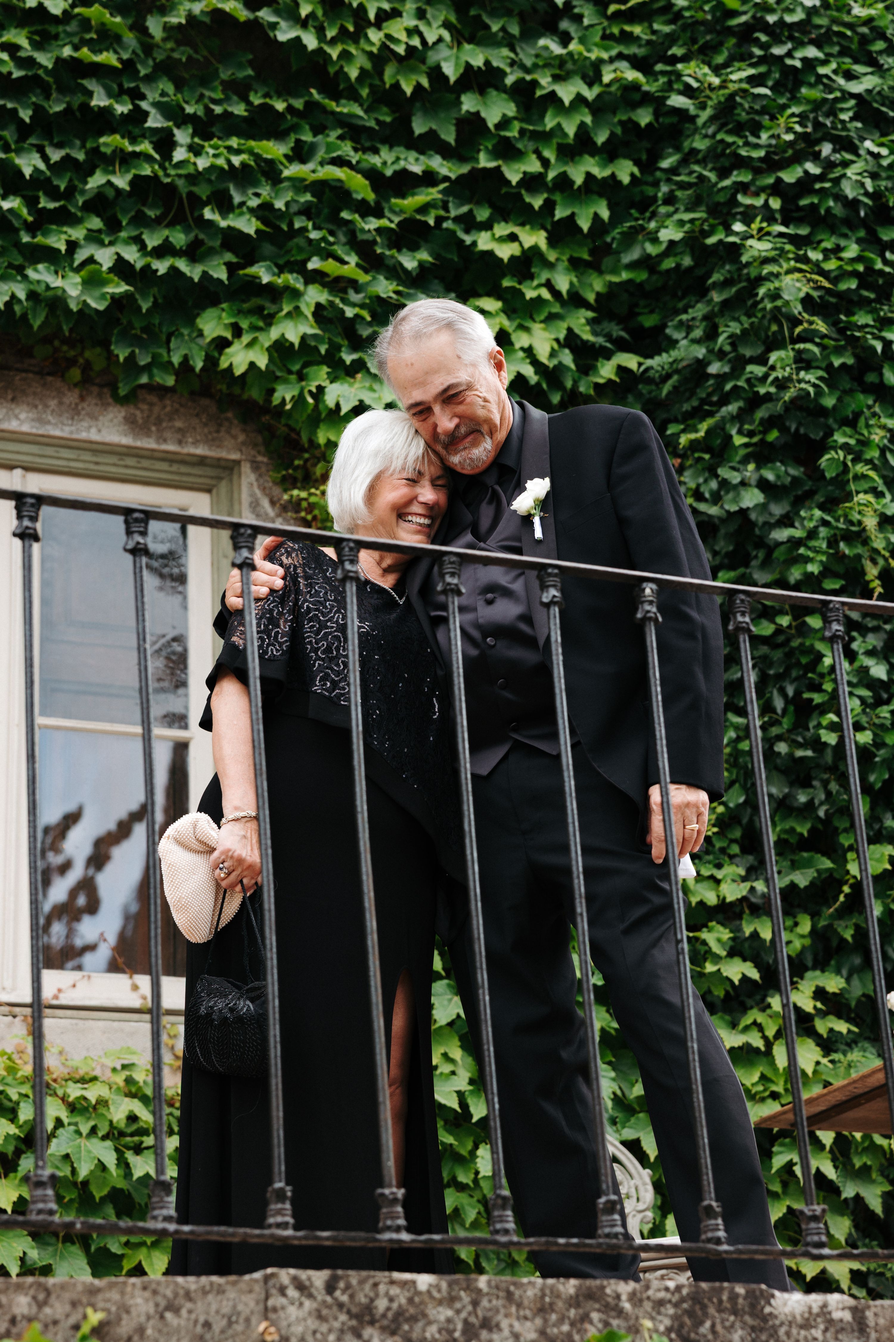 Parents of the bride proudly looking down on the wedding couple from above a staircase